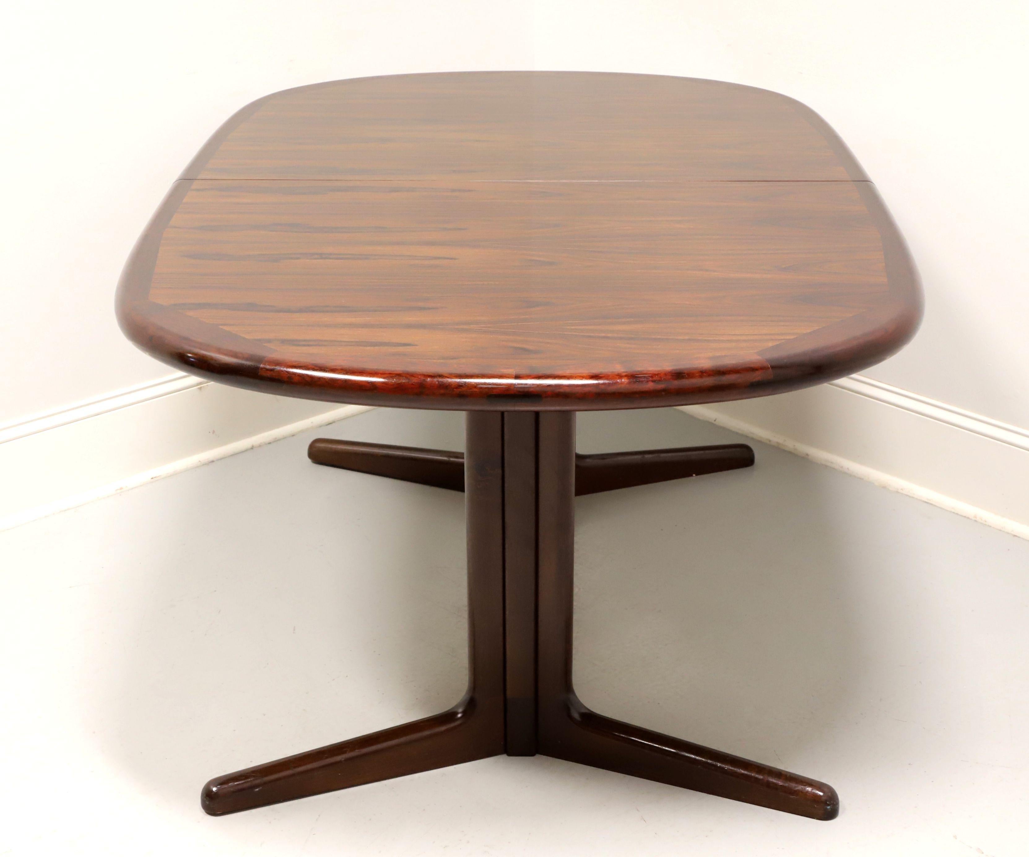A tapered rectangular shaped dining table in the Danish Modern style by Edvard Valentinsen. Rosewood with a stunning grain to the top, smooth rounded apron and trestle style base. Includes two 19 inch extension leaves for placement on wood expansion
