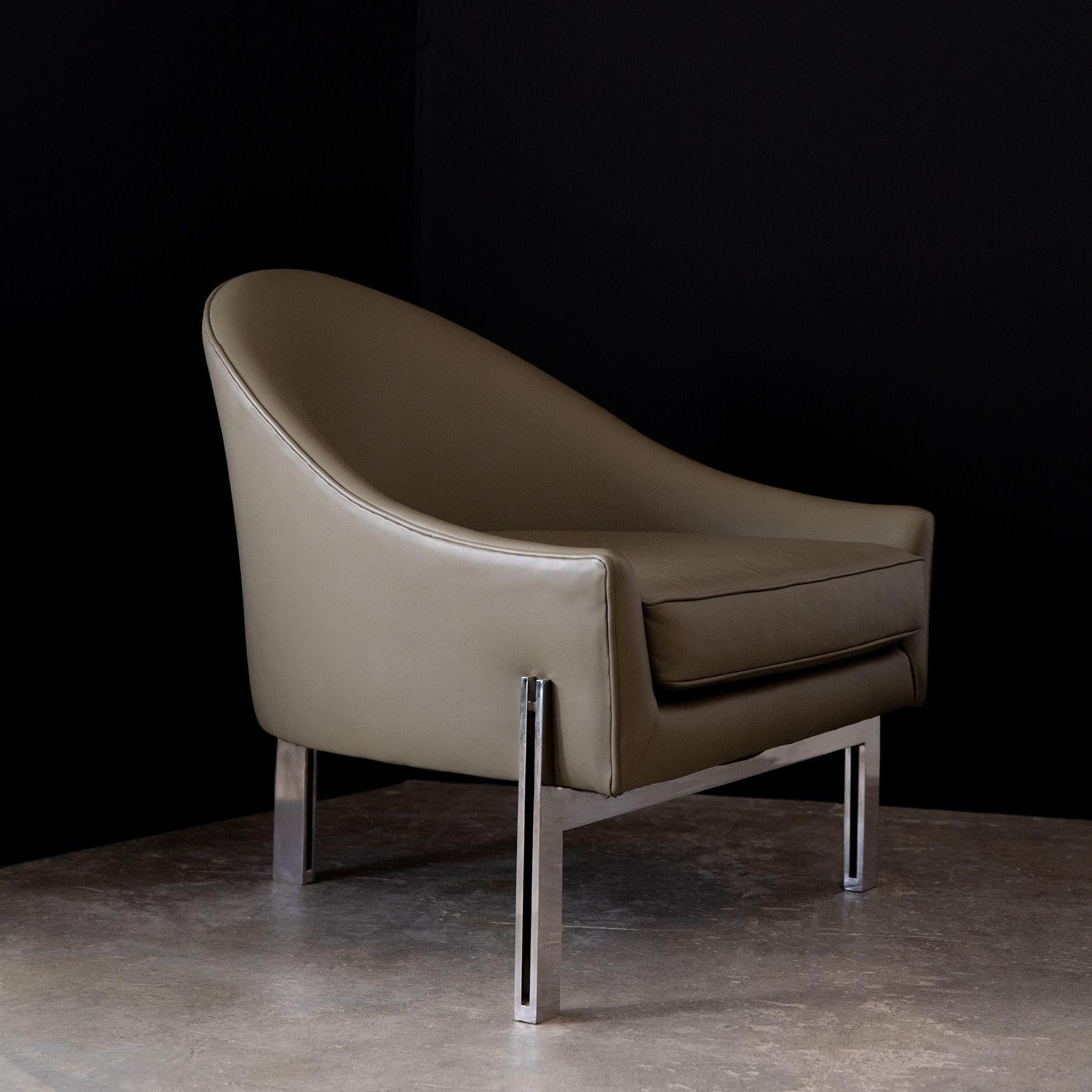 These arch-back club chairs were designed by Edward Axel Roffman and commissioned in the 1960s by Atlas Steel in Chicago. This design was typically made with wood legs but these examples are constructed with solid polished flat bar stainless steel