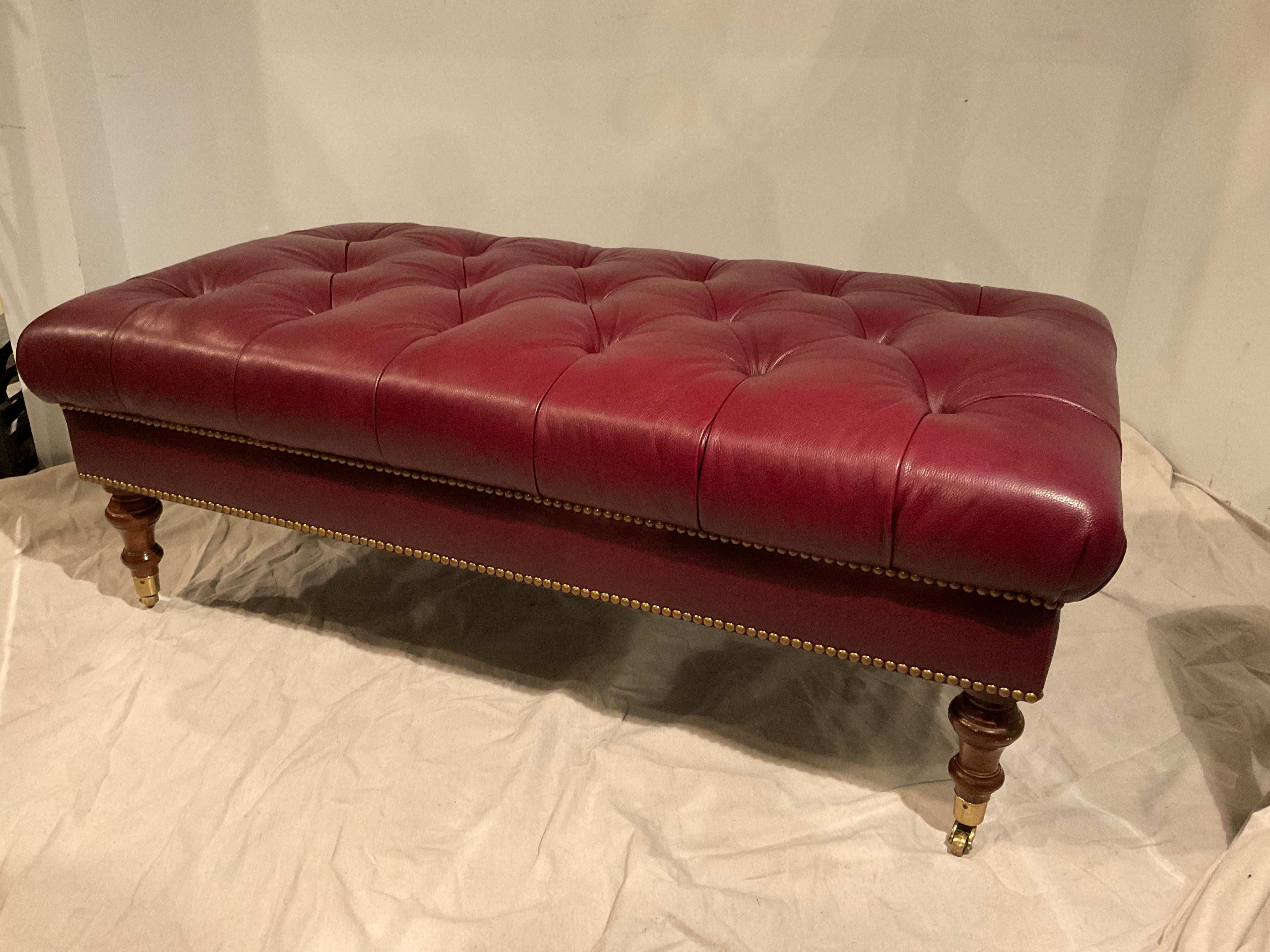 Edward Ferrell red leather tufted ottoman on brass casters. Light spot on leather as shown in image 7.