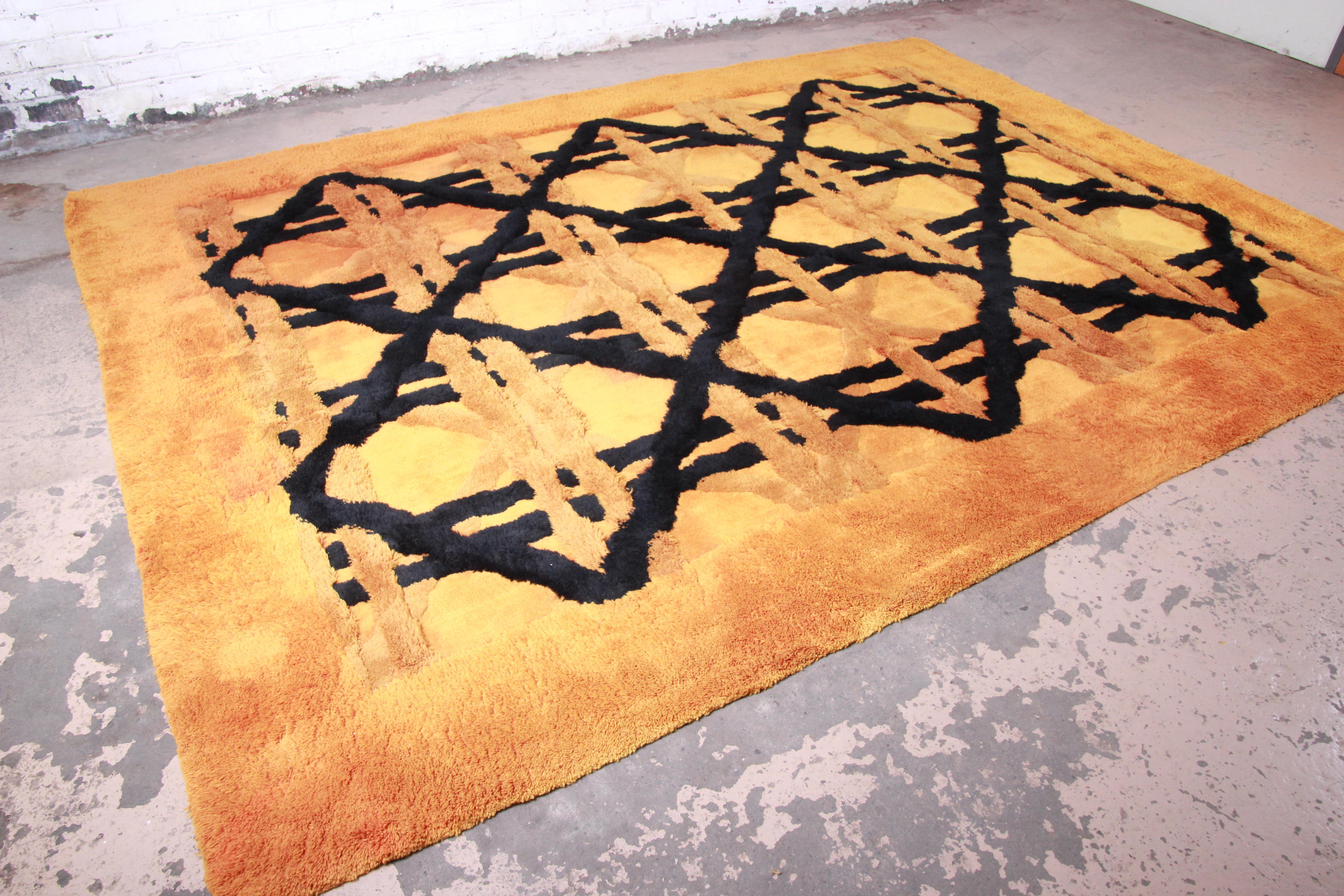 A unique and exceptional sculpted shag rug made by Edward Fields in 1974. The rug has a very thick and plush wool pile, with an orange field and black geometric design. The original label is present. Perfect for any modern or mid-century modern