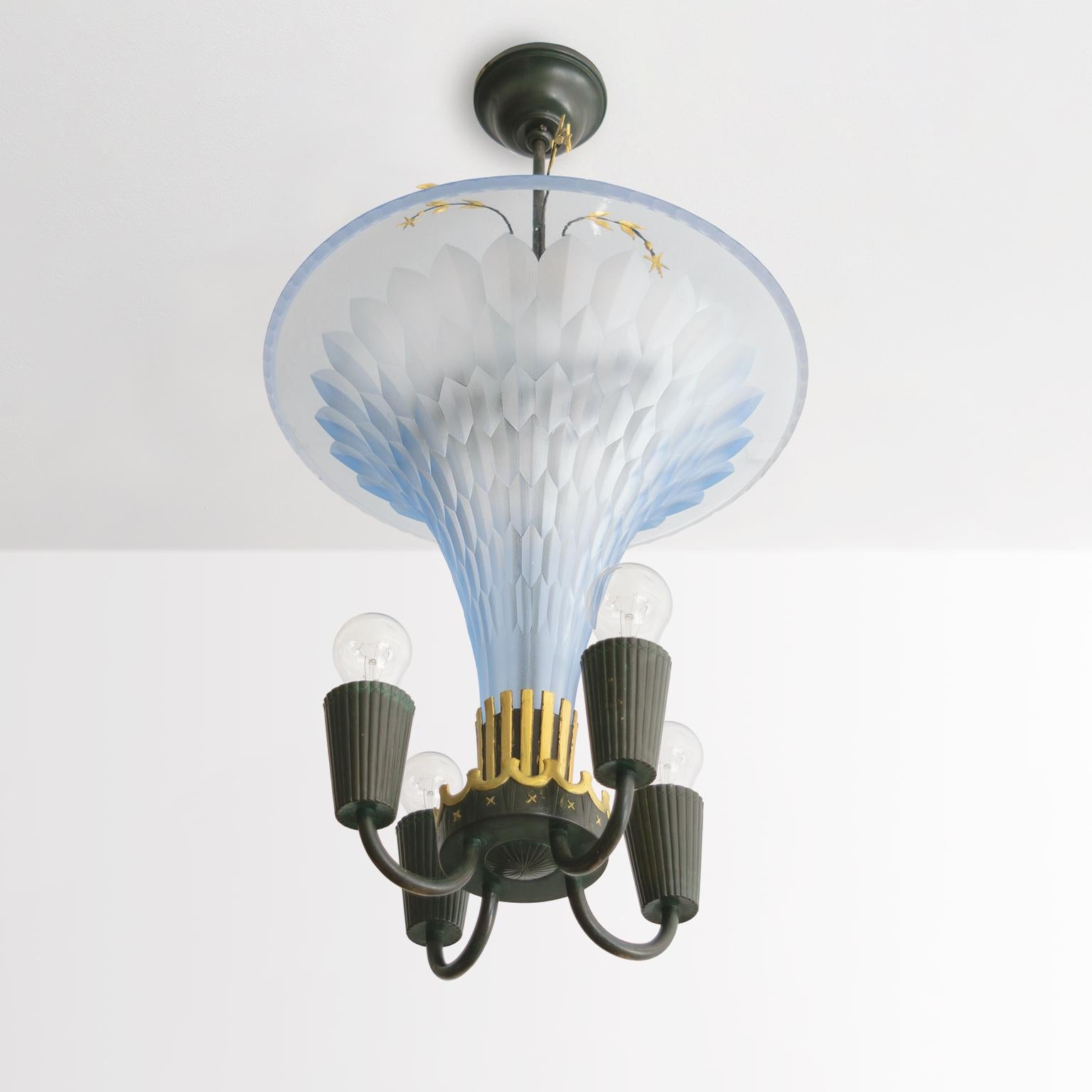 Swedish glass master Edward Hald designed this chandelier with Erik Tidstrand for Orrefors in the late 1920’s. The etched blue glass funnel rises from a patinated and golden ribbed holder which in turn sits within a finely detailed crown. Besides