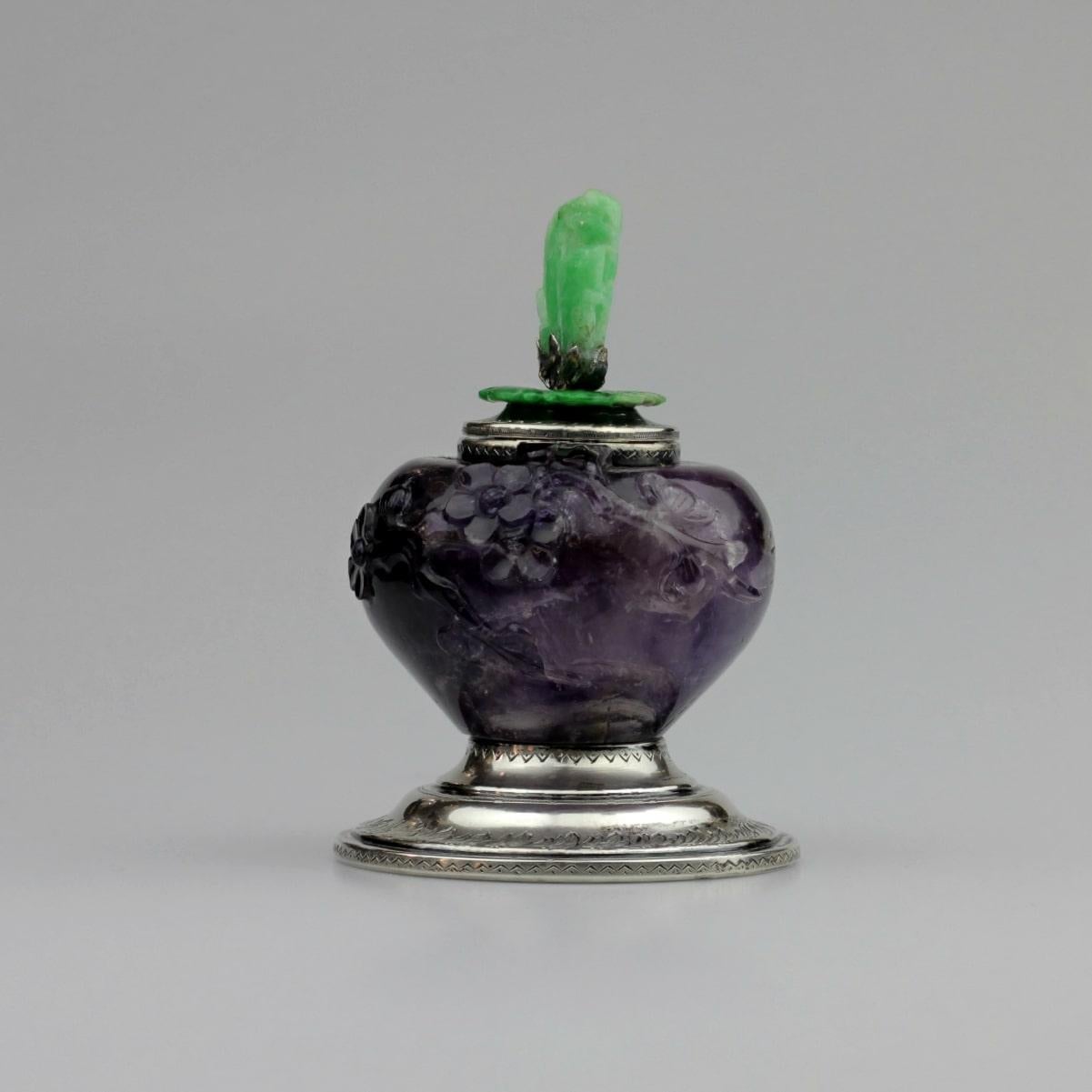 An incredible decorative inkwell by New York identity, Edward I. Farmer. The piece is crafted from a large piece of amethyst in a carved prunus pattern topped with a jadeite finial, all mounted in sterling silver. The silver foot on this piece is