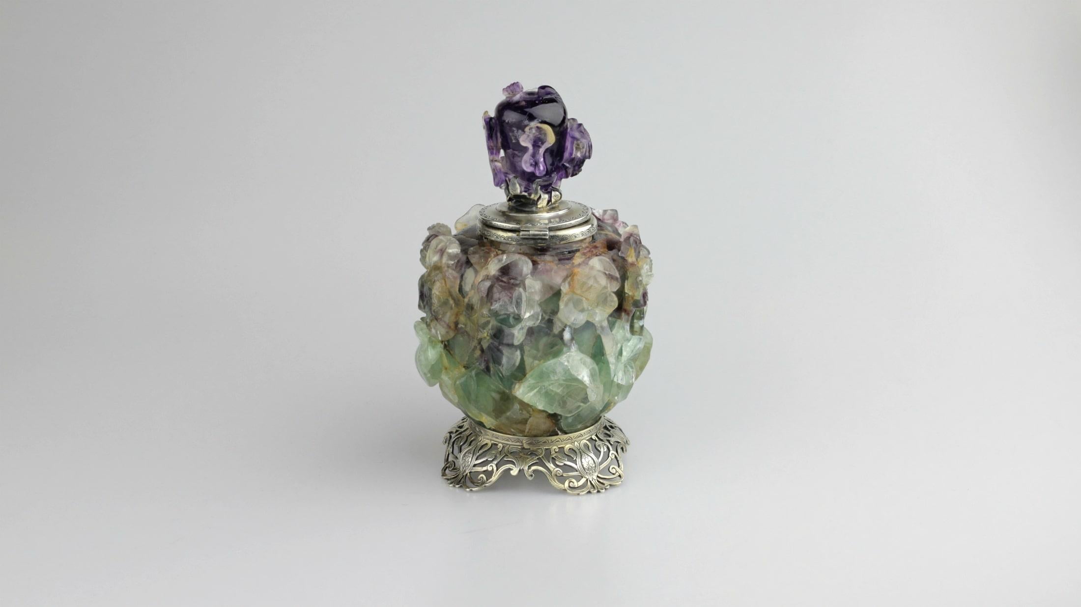 A monumental inkwell by New York identity, Edward I. Farmer. The piece consists of a large piece of carved fluorite and a carved amethyst finial which has all been set in sterling silver. The mount for these carved stones is elaborate with a floral