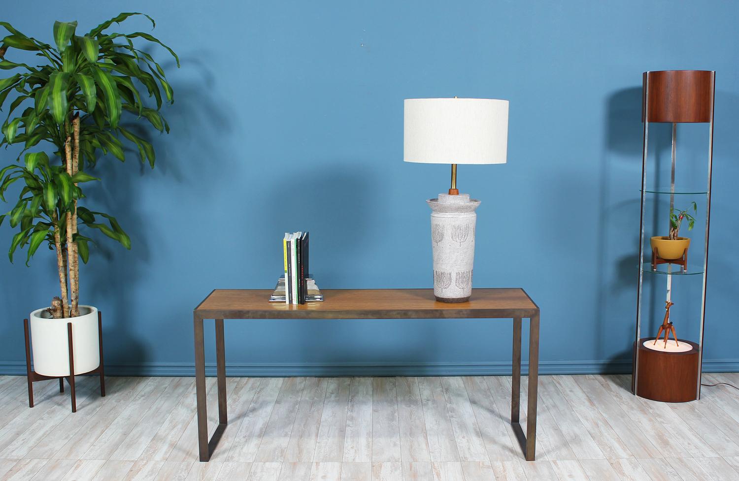 A Mid-Century modern console table designed by Edward J. Wormley for Dunbar in the United States circa 1950’s. Beautifully crafted with a solid bronze frame that supports the wood top, the combination of linear lines and open space makes this