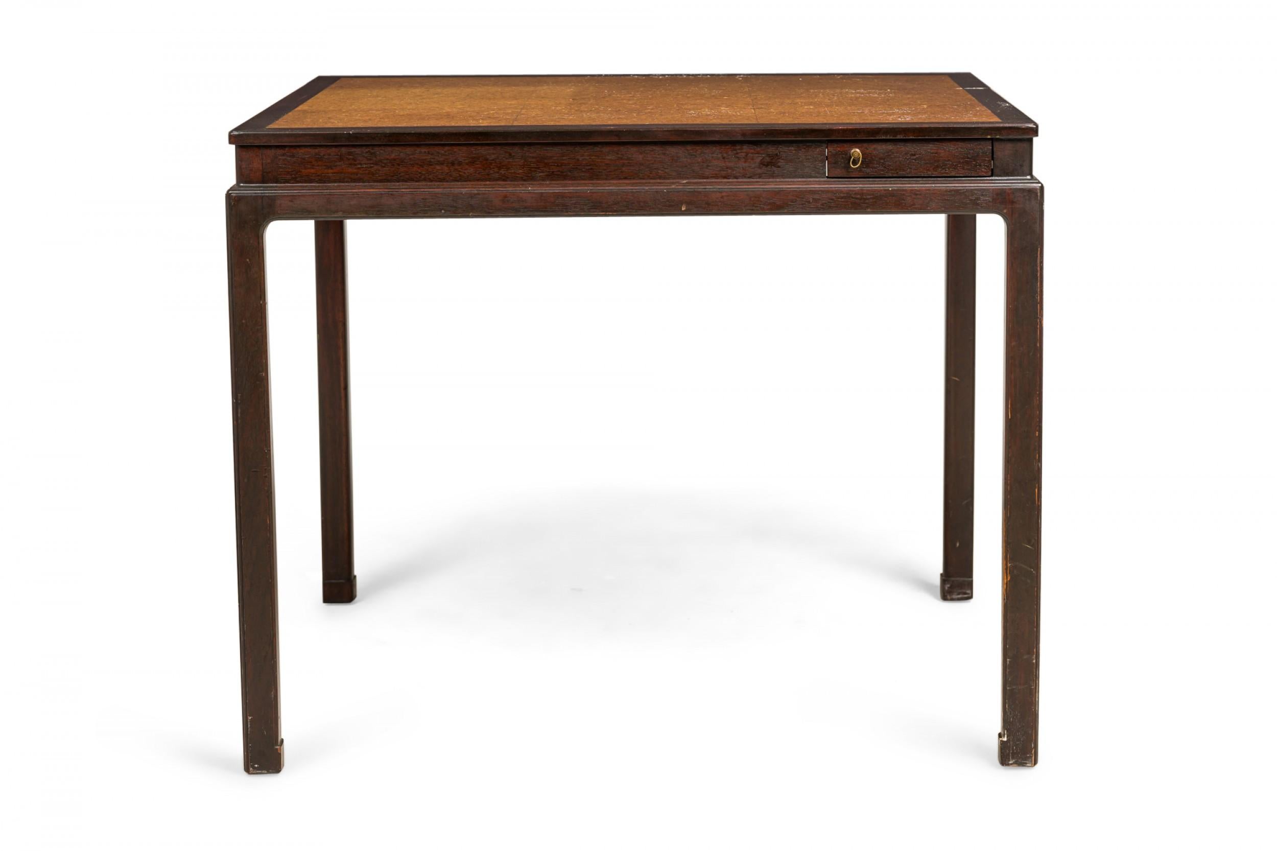 American Mid-Century square game table with a dark wooden frame and and inset cork top, featuring four concealed drink trays that pivot outward from each corner with small brass ring drawer pulls. (EDWARD J WORMLEY FOR DUNBAR FURNITURE COMPANY).
 