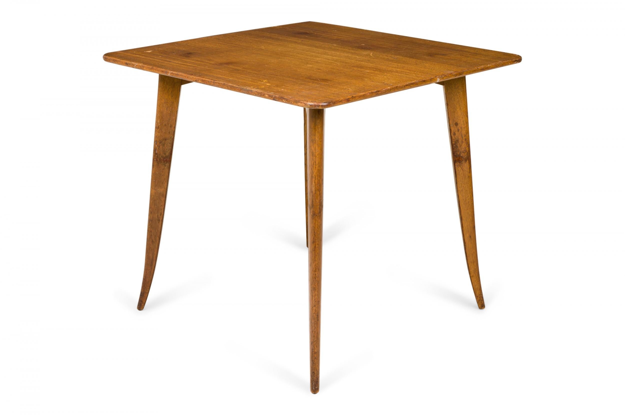 American mid-century wooden game table with a square tabletop with rounded corners, resting on four sabre legs. (EDWARD J WORMLEY FOR DUNBAR FURNITURE COMPANY)