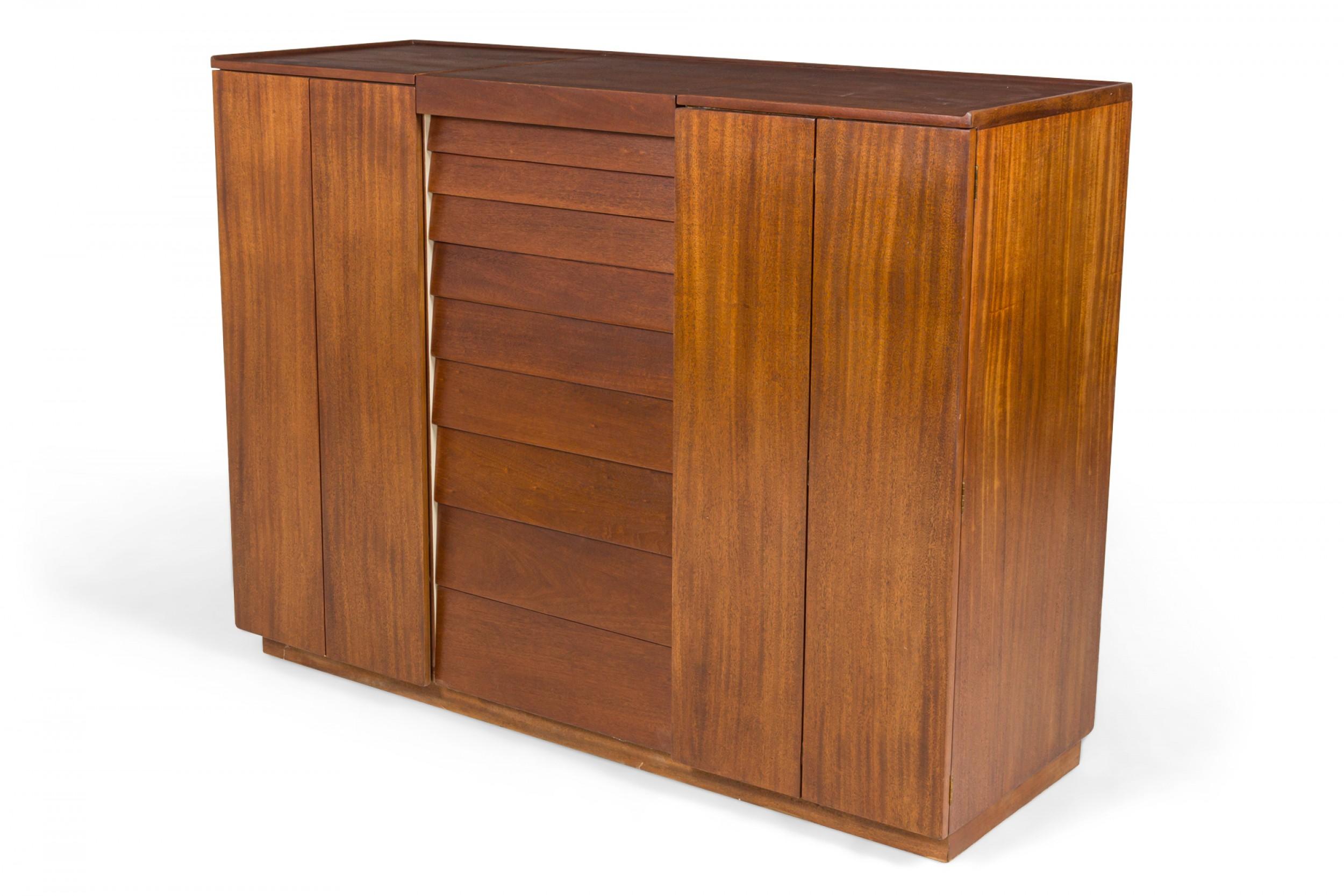 American Mid-Century walnut chifferobe / dressing cabinet with a central section with 9 drawers descending in size from top to bottom, flanked on either side by two door cabinets, with a central lid that opens upward to reveal a concealed mirror and