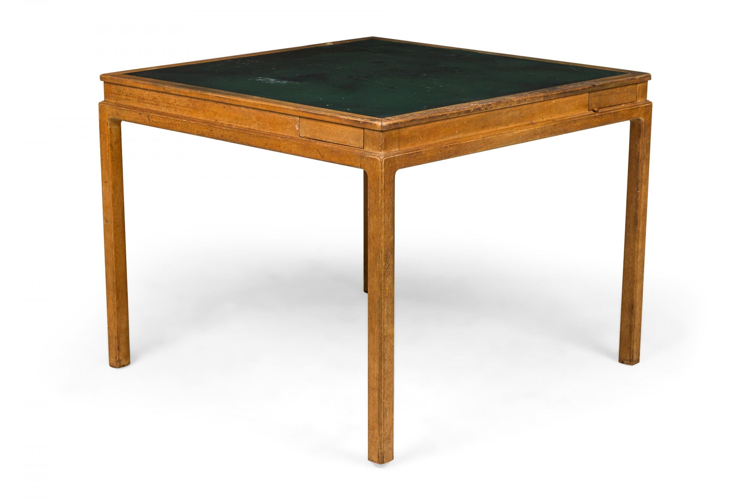 American mid-century game table with a wooden frame and a square inset green leather top, resting on four square wooden legs. (EDWARD J WORMLEY FOR DUNBAR FURNITURE COMPANY)