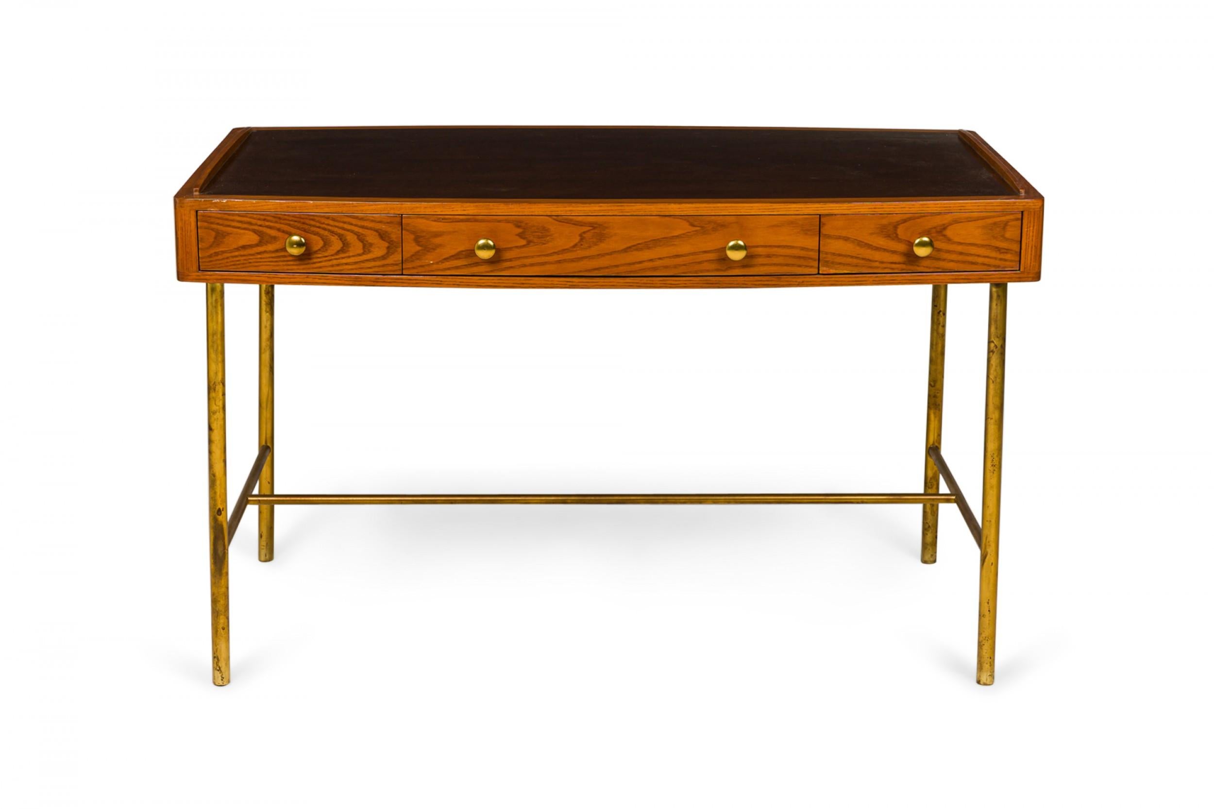 American mid-century writing desk with a rectangular top with a wooden frame and deep brown laminate desktop with three drawers with circular brass drawer pulls, resting on a brass tube stretcher base. (Edward J Wormley for Dunbar Furniture