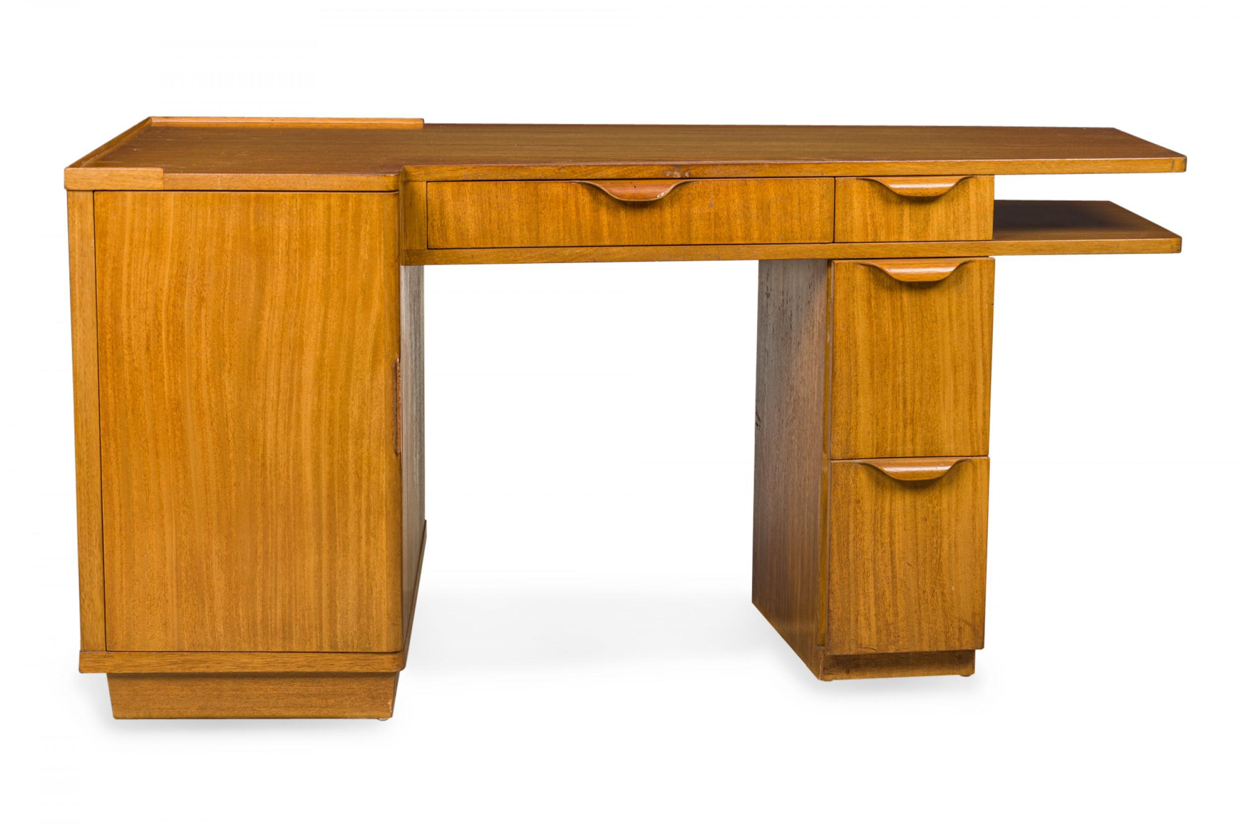 American mid-century wooden pedestal desk with four drawers with wooden drawer pulls, a shelf on the right-hand side below the tabletop, and a cabinet to the left with an extendable writing surface concealed within. (EDWARD J WORMLEY FOR DUNBAR