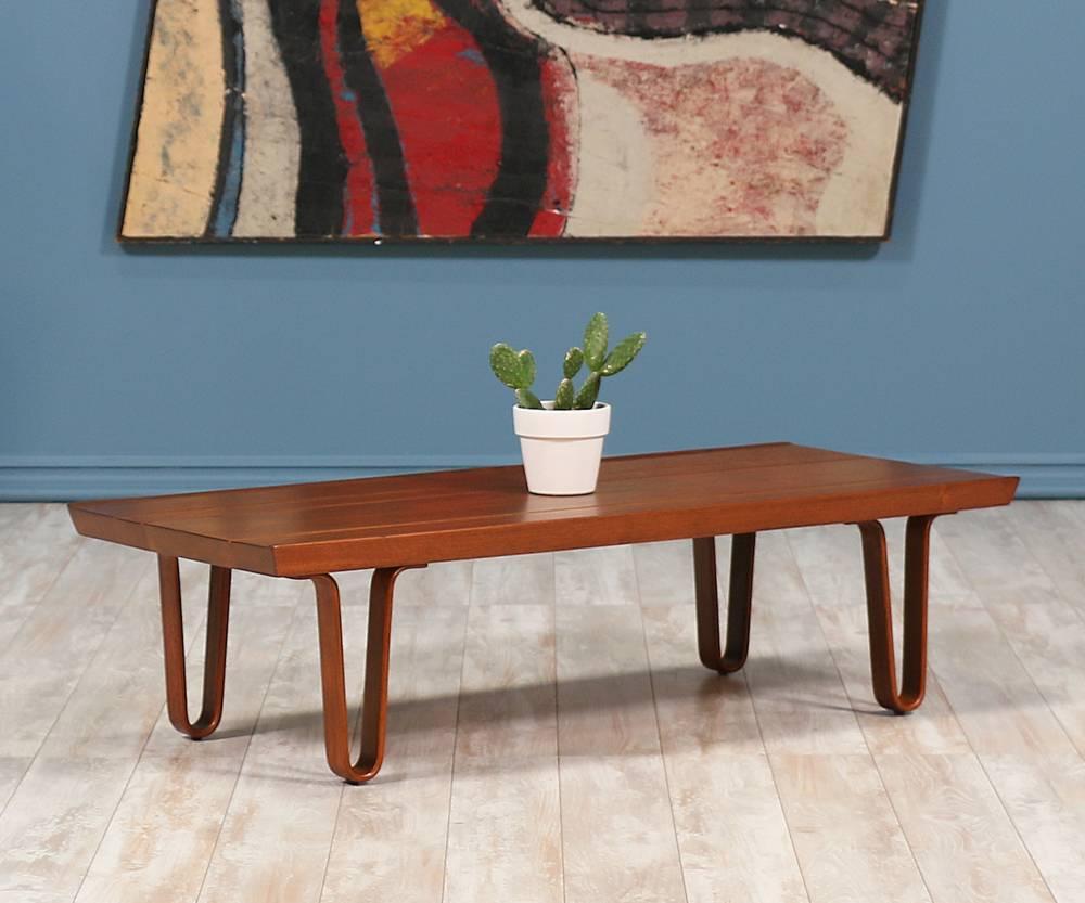 Mid-Century Modern “Long John” bench or coffee table designed by American furniture designer, Edward J. Wormley, for Dunbar in the United States, circa 1940s. This stunning design is a smaller version and features a laminated top comprised of solid