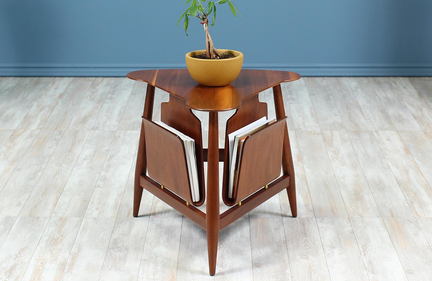 Modernist magazine table designed by Edward J. Wormley for Dunbar in the United States circa 1950’s. Professionally restored by our expert craftsmen, this Mid-Century modern design features a walnut wood frame and a triangular table top with rounded