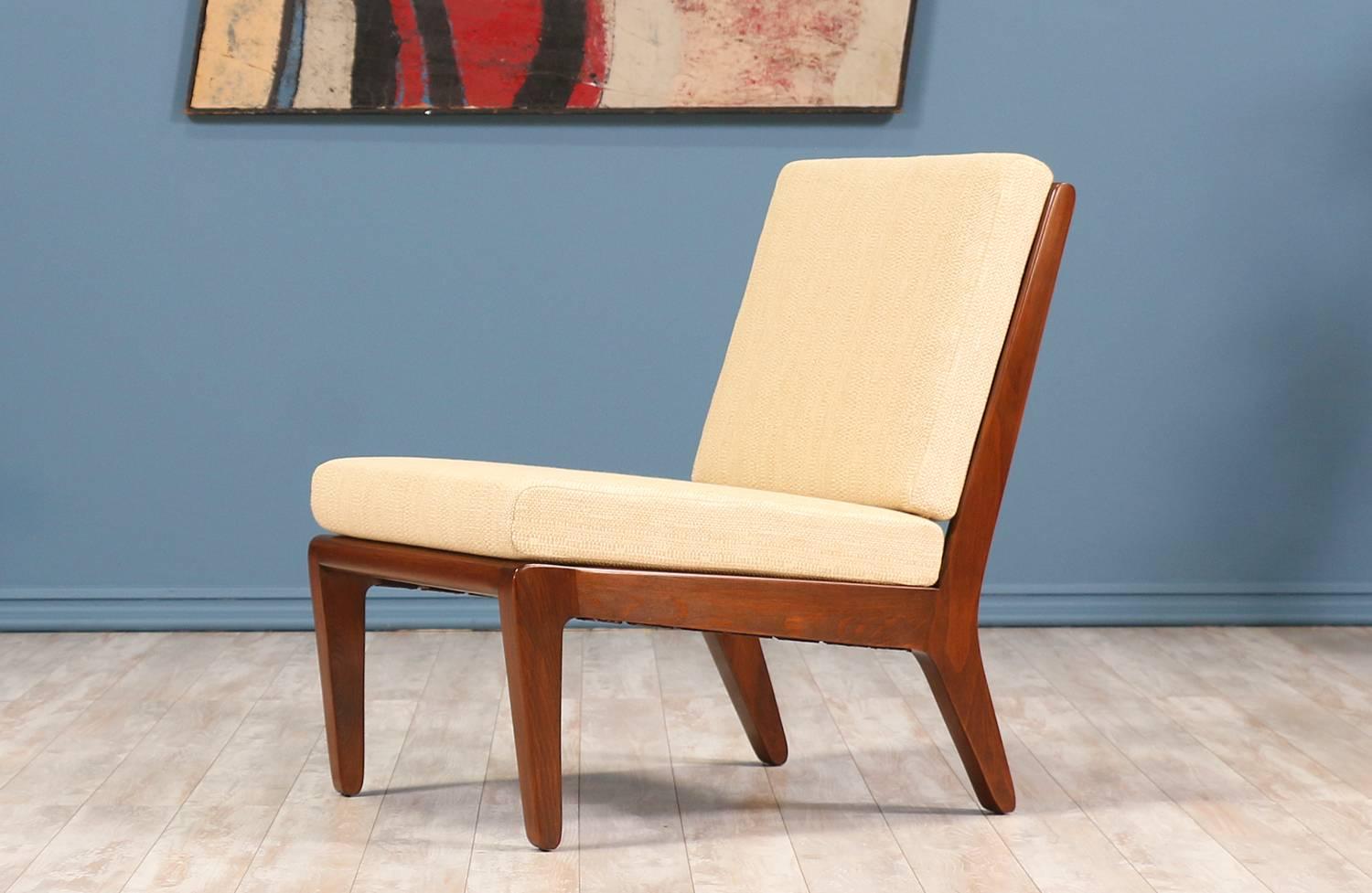 Lounge chair designed by Edward J. Wormley for Drexels “Precedent” line in the United States circa 1940’s. Featuring a walnut-stained beech wood frame with a slatted back for support and angled tapered legs. The cushions have been replaced and