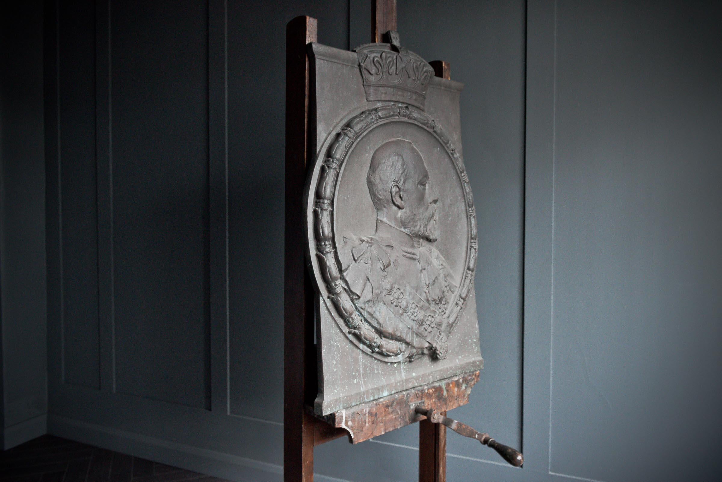 This exceptional cast bronze relief plaque depicts His Majesty King Edward VII in high profile, majestically attired in the full regalia of the Order of the Garter, encircled by a laurel and garter motif and surmounted by a royal crown bearing the