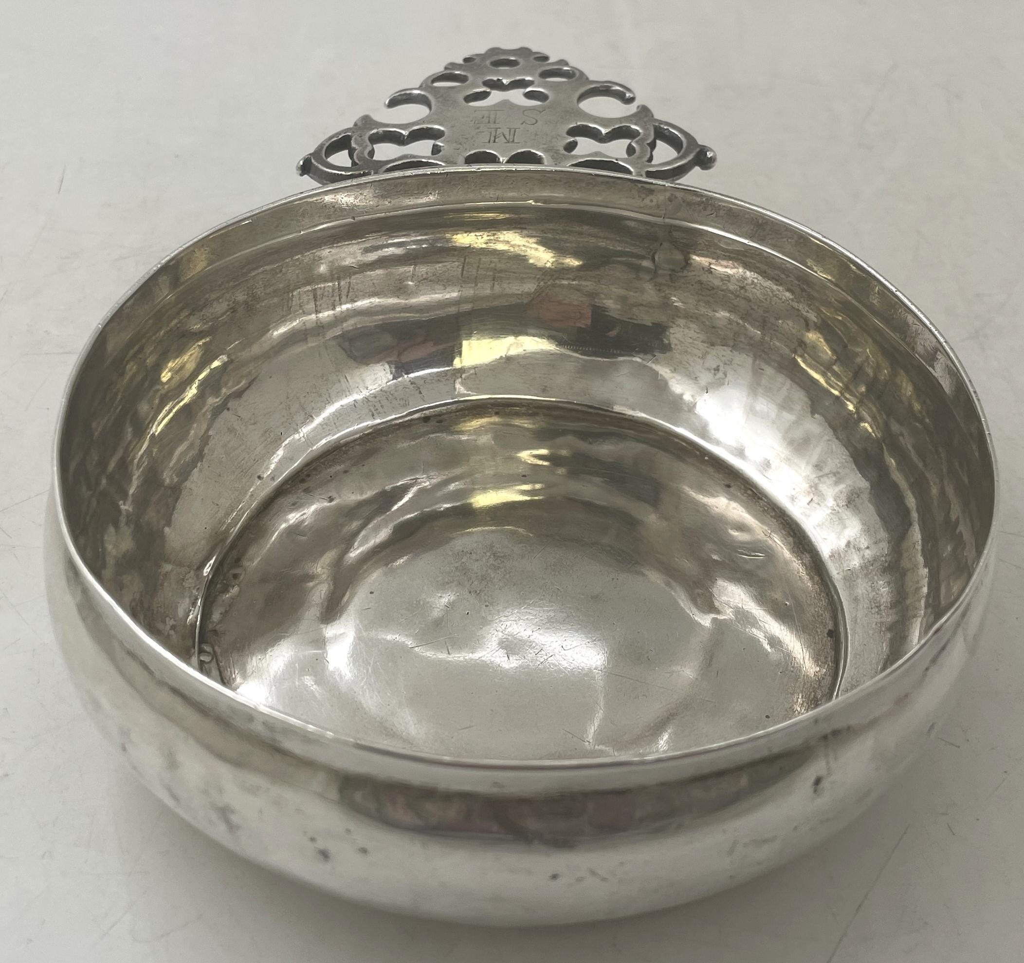 Edward Winslow rare silver porringer from the early 18th century. It measures 7 1/2'' in depth including the handle by 5 1/8'' in width by 1 7/8'' in height, weighs 7.8 troy ounces, and bears hallmarks as shown. The handle is adorned with the