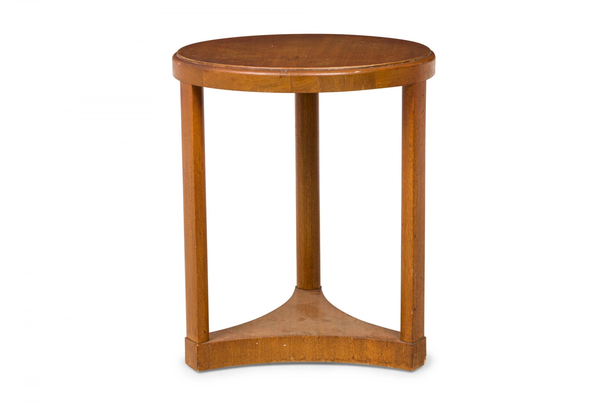 American Mid-Century round wooden side / end table with a circular top with beveled edge resting on three vertical rectangular supports connected to a triangular scooped side base. (EDWARD WORMLEY)(Similar shorter table: DUF0638)
