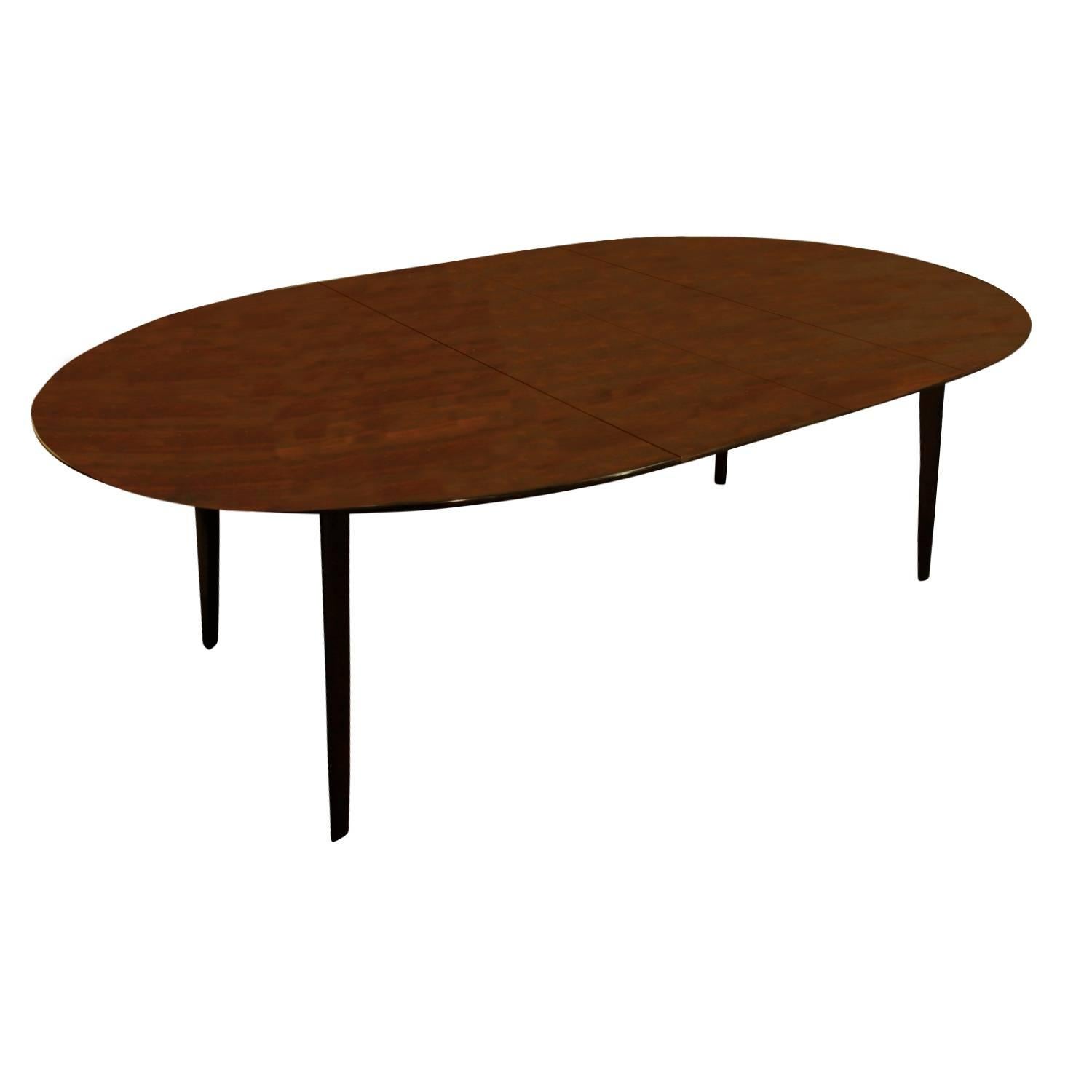 Dining table in walnut with two leaves, angular leg design, by Edward Wormley for Dunbar, American, 1950s (signed with Dunbar metal label on bottom).

Without leaves: W 60 inches.