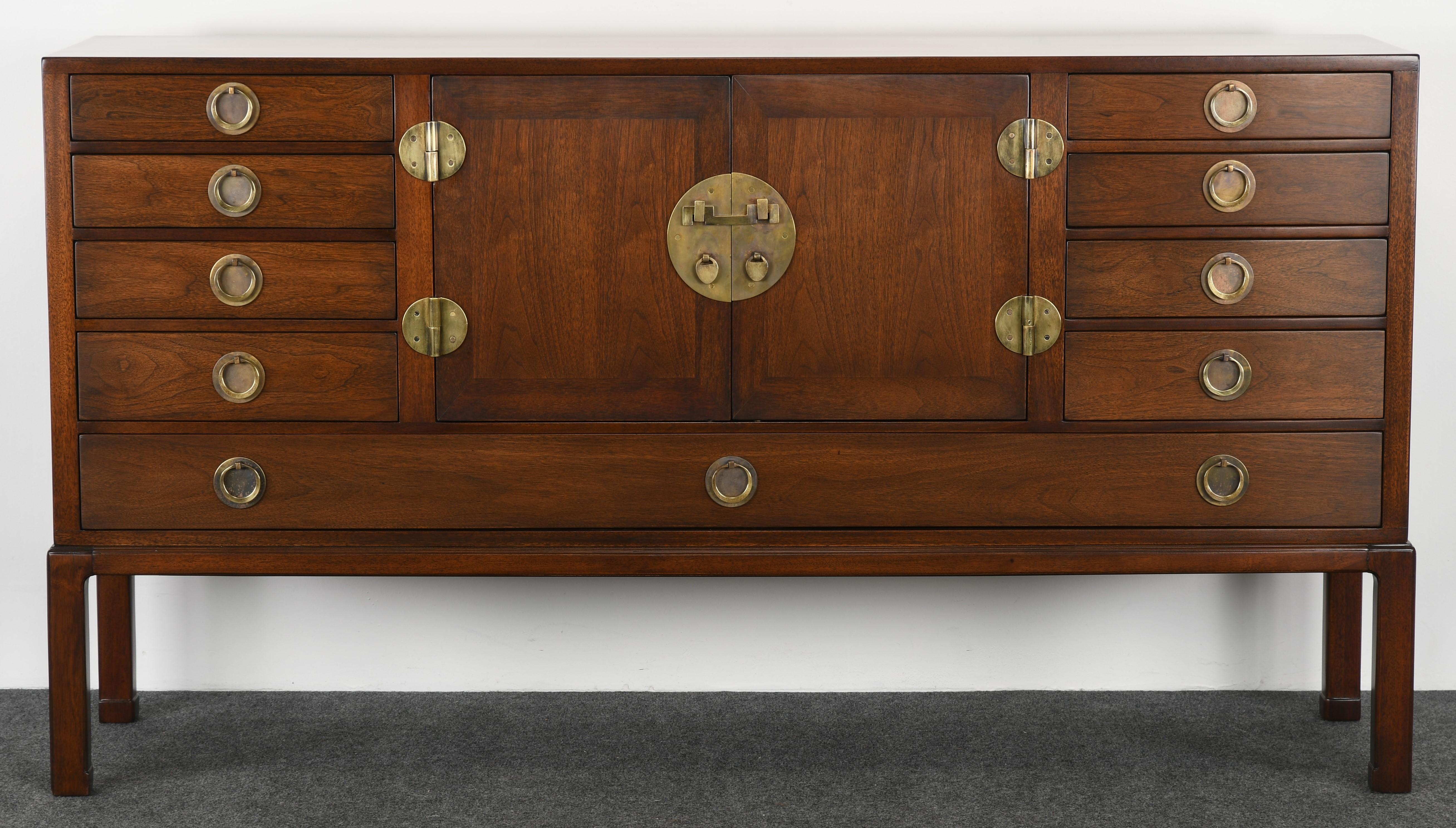 A gorgeous Edward Wormley Asian walnut credenza for Dunbar modern, model #4579. Multiple drawers, including divided utensil drawers and pull out glass serving tray. The credenza is accented with beautiful Asian brass hardware. Hardware can be