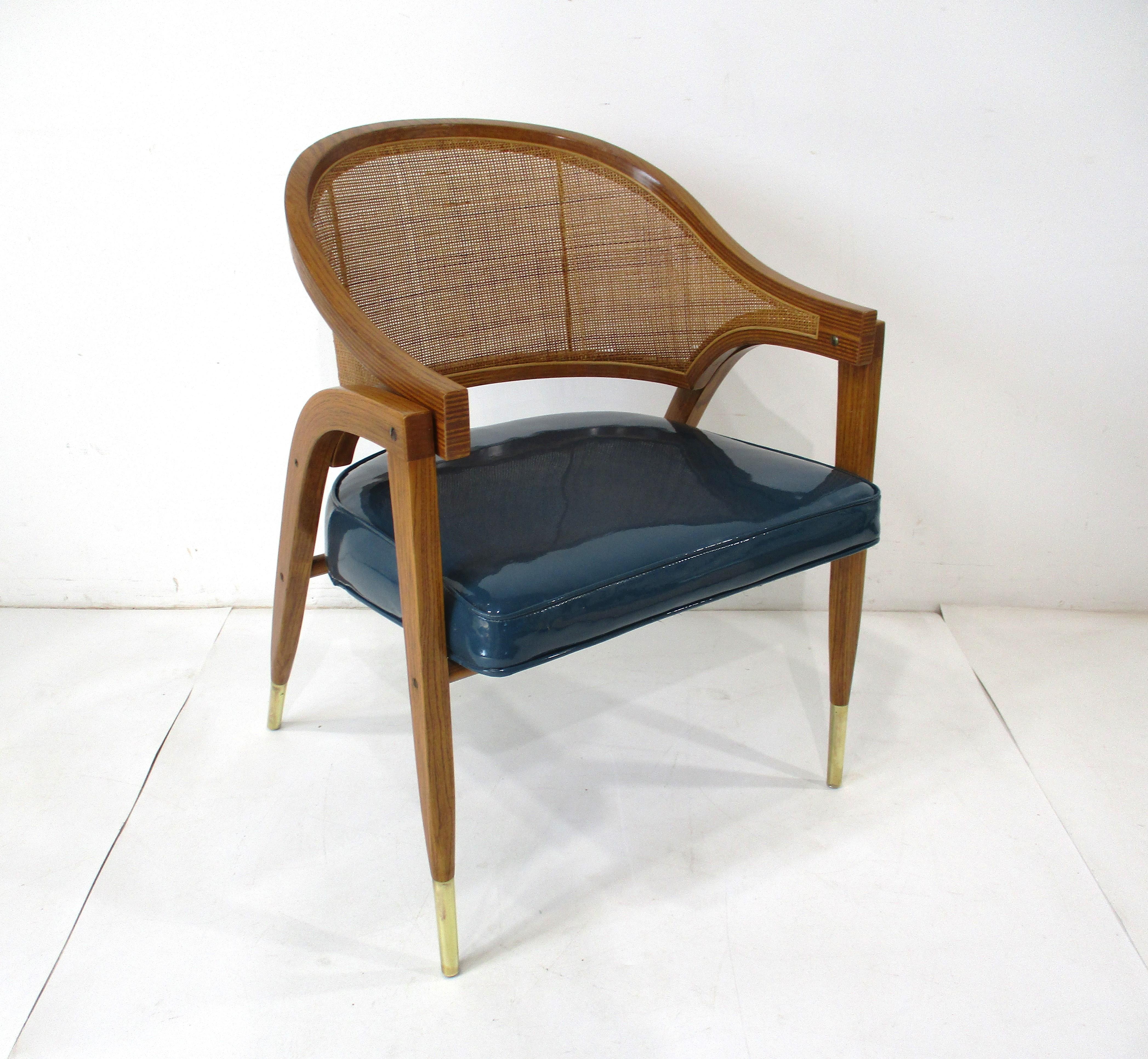 A very well crafted arm chair with sculptural bent wood frame , woven caned backrest , brass details and upholstered seat cushion . This high styled chair is a statement piece in any interior with attention to the small details typical of the iconic
