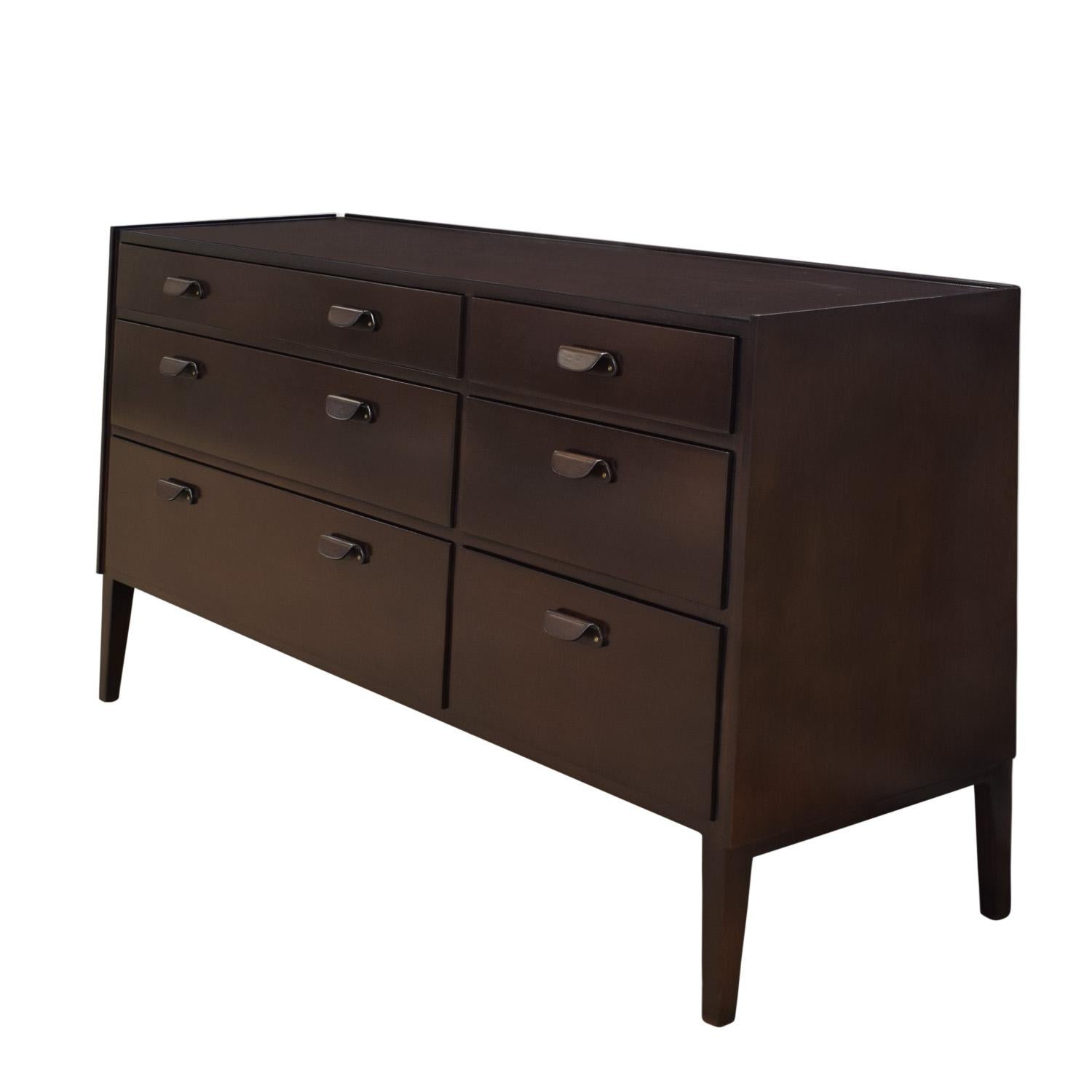 Elegant chest of drawers model 5562 in dark mahogany designed with a gently slanted front with 9 drawers, each with a hand-carved pull, by Edward Wormley for Dunbar, American 1955 (signed “Dunbar Berne Indiana” on metal label in top left drawer.)