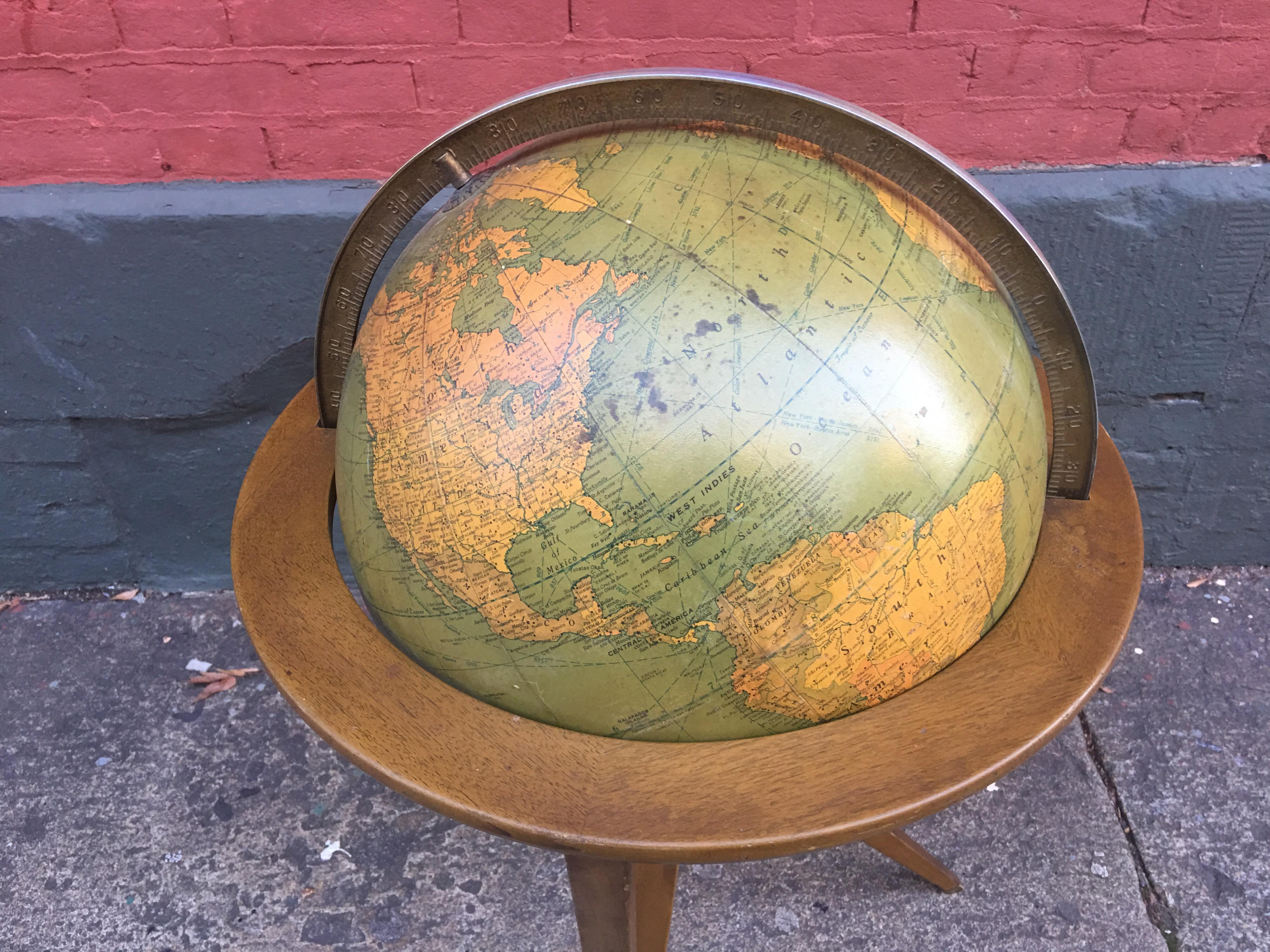 Edward Wormley Rand McNally World globe on stand. Paper over glass ball, globe spins and pivots in stand. Wood base has brass accents. Globe shows some slight staining and losses to bottom area/ south pole.