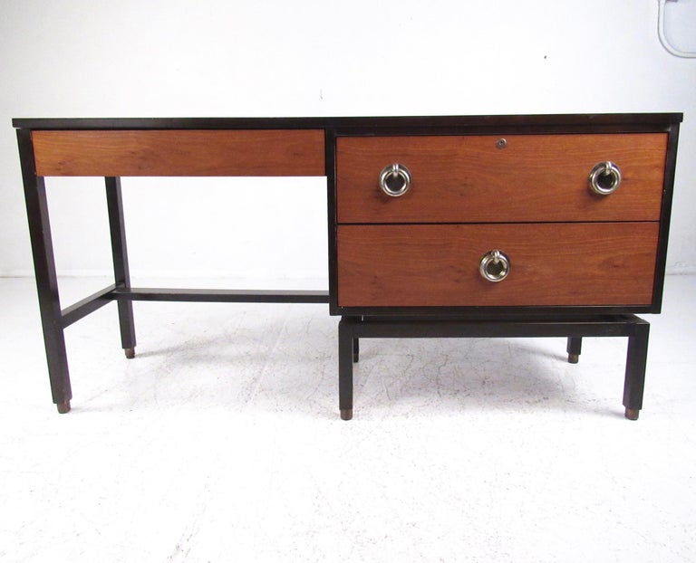 This striking midcentury writing desk features iconic Edward Wormley design including large metal ring drawer pulls, formica style top, and two tone construction. The striking mix of ebonized wood frame with lighter walnut wood tone drawer fronts