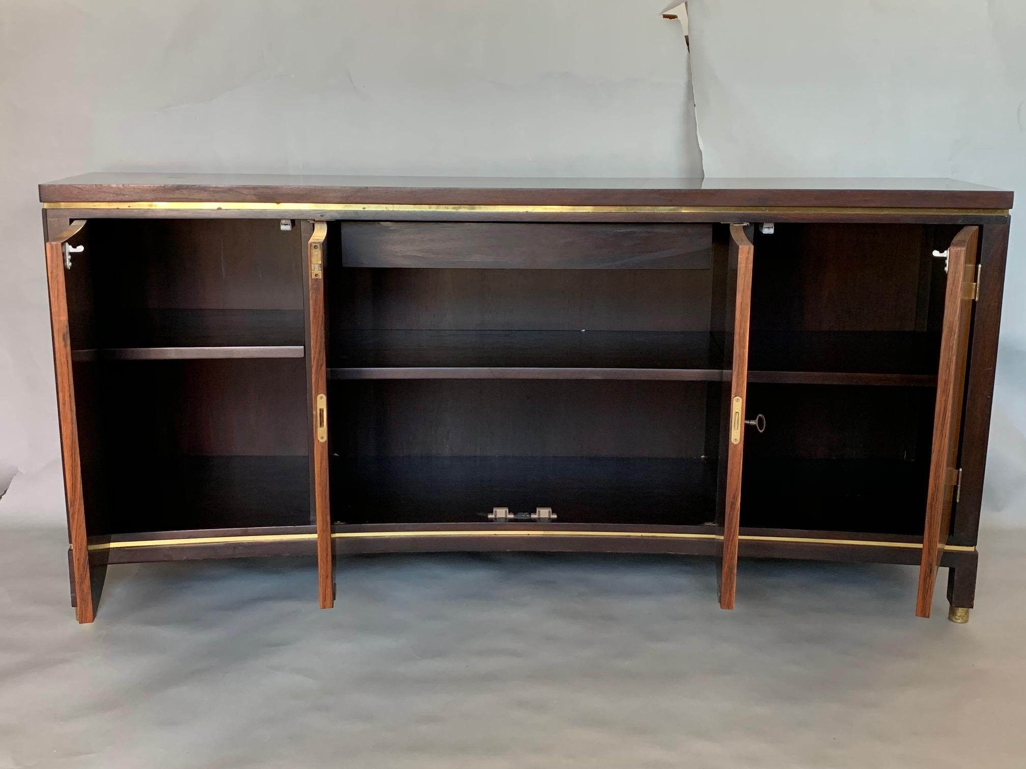 A rare credenza designed by Edward Wormley and custom made by Dunbar for Mellin Furniture Galleries, Warren, Michigan, circa 1969. Curved front rosewood doors, walnut case with plastic wood grain top, brass ferrules on legs. Measuring 65.5