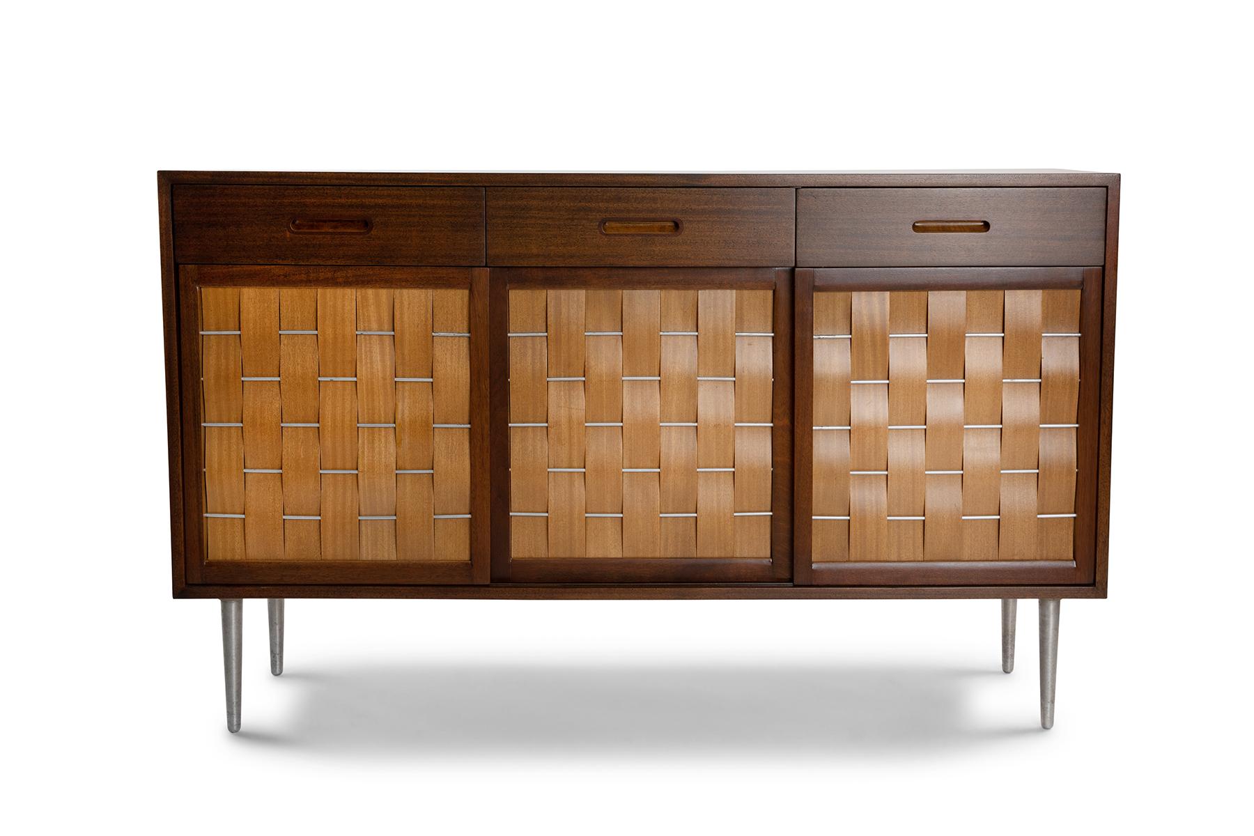 Edward Wormley for Dunbar woven front sideboard, circa mid 1950's. This example has a striped African mahogany case, stainless steel legs and lots of interior storage. It has been newly and impeccably refinished.