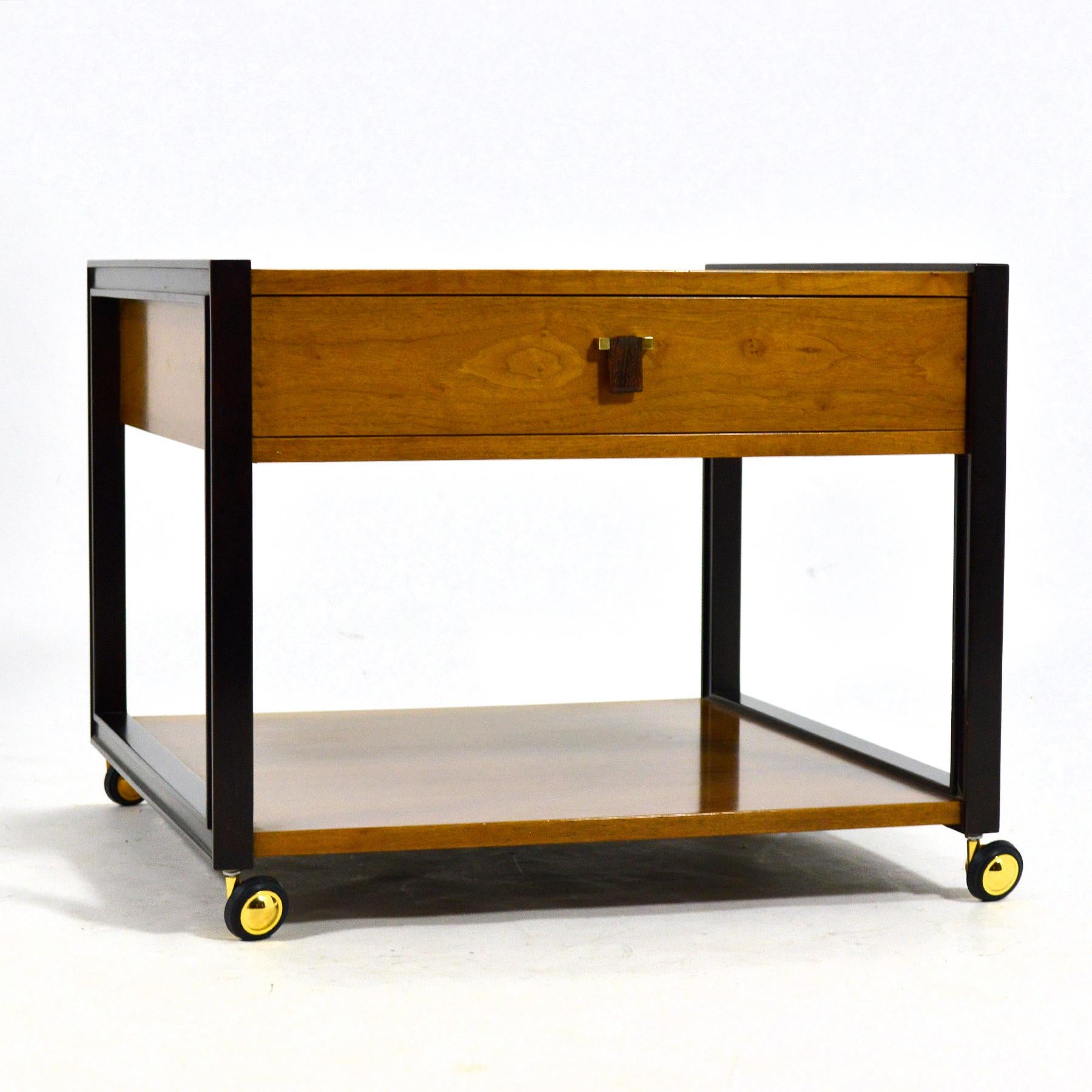 Cette table d'appoint Ed Wormley de Dunbar, aux proportions généreuses, présente une caisse et une étagère en noyer soutenues par des pieds en acajou et des pieds ronds à roulettes pour faciliter les déplacements. Il est doté d'une jolie petite
