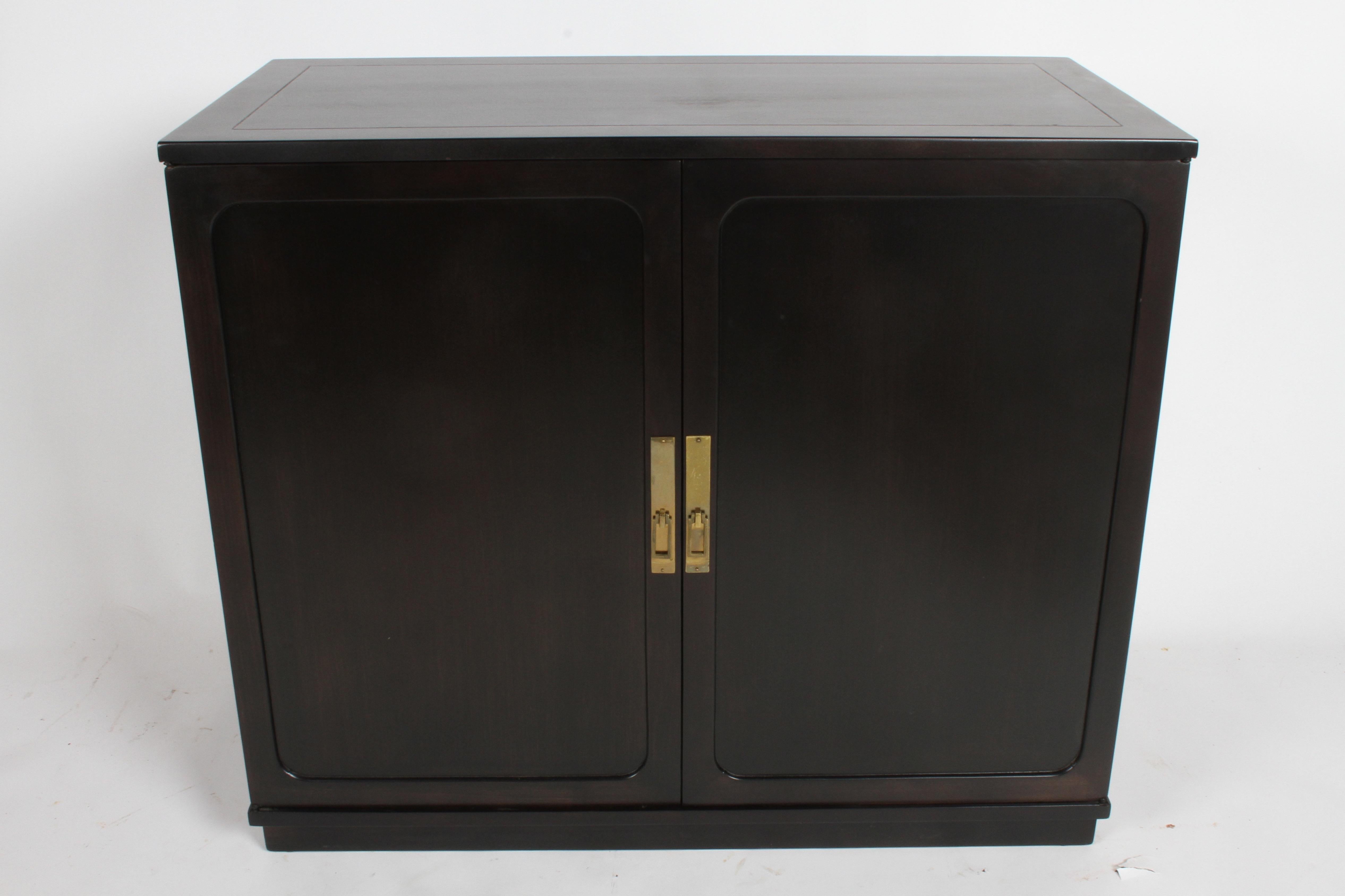 Edward Wormley two-door cabinet in ebonized silver elm with brass hardware, circa 1948. The one shown has recently sold, but have another with slightly different hardware available, please inquire. Interior has two sliding drawers over open space.