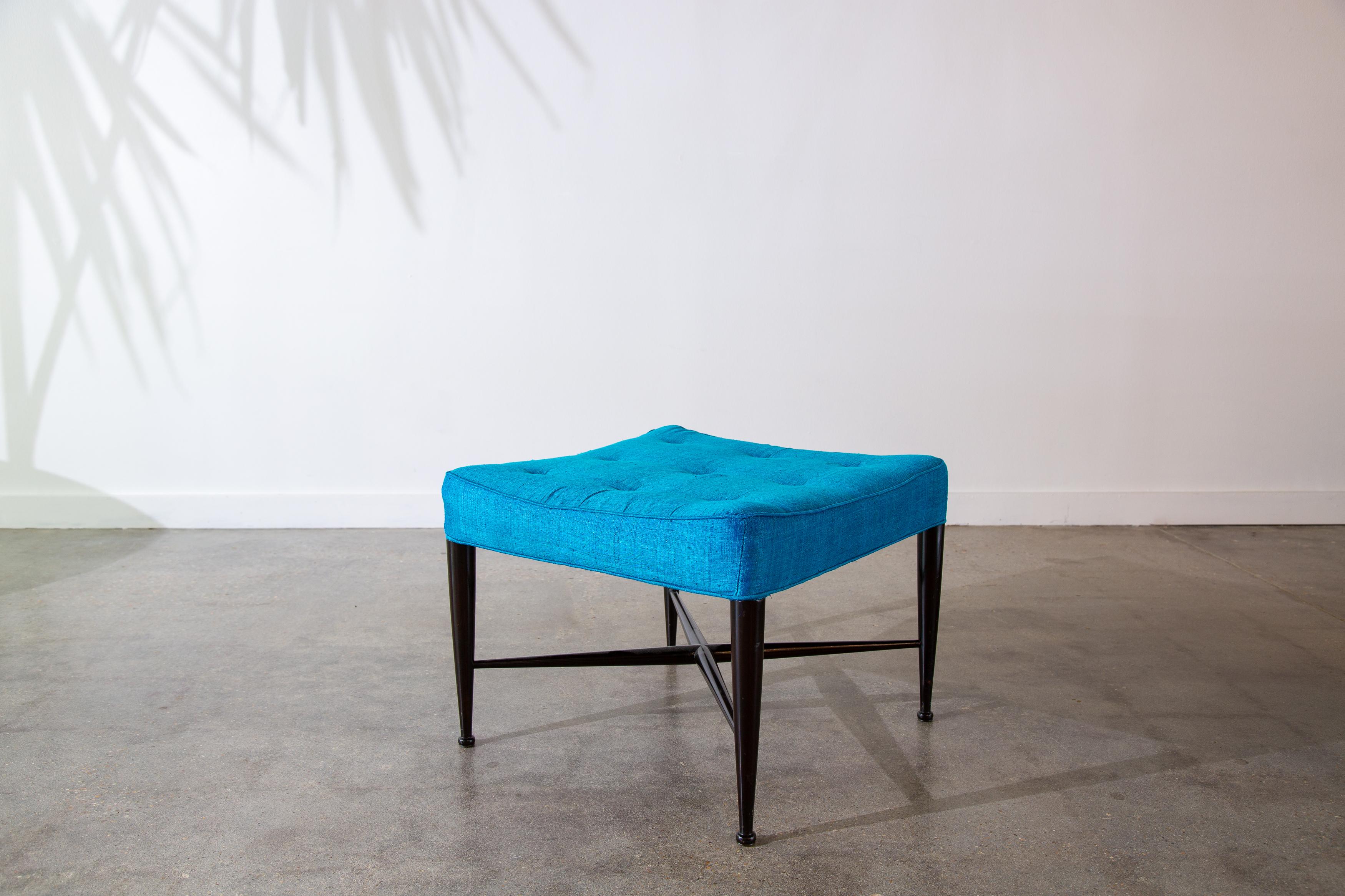 Una otomana / taburete Tebas de los años 50 diseñada por Edward Wormley para Dunbar Furniture Company de Berne Indiana. Un cojín cuadrado empenachado con laterales ensillados flota sobre patas cónicas con pies de bola redondeados y una cruceta en X