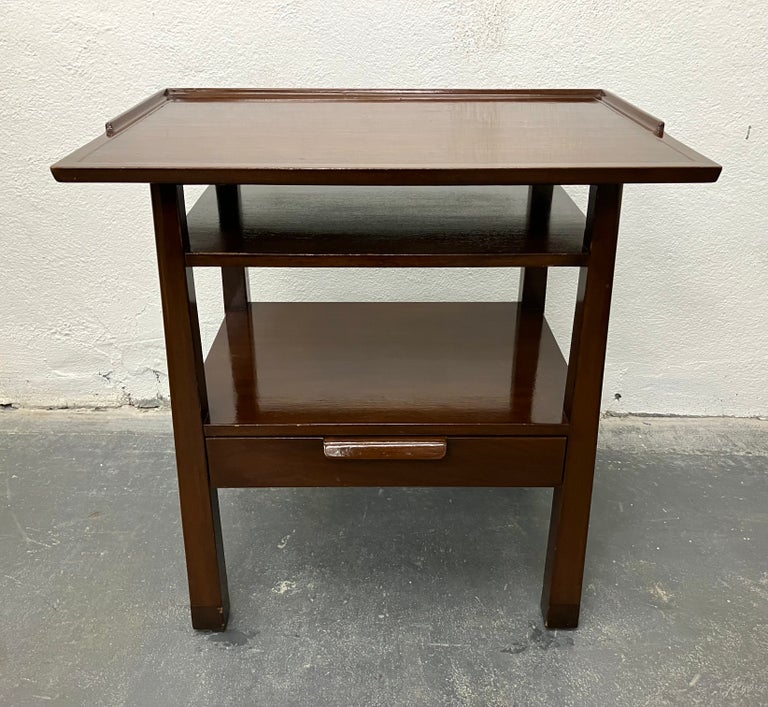 Architectural Edward Wormley design in mahogany with curved bentwood drawer pull, gallery trimmed top, reverse leg taper, and leather capped feet. An interesting modern update on an Arts & Crafts form. Works equally well as side or occasional table