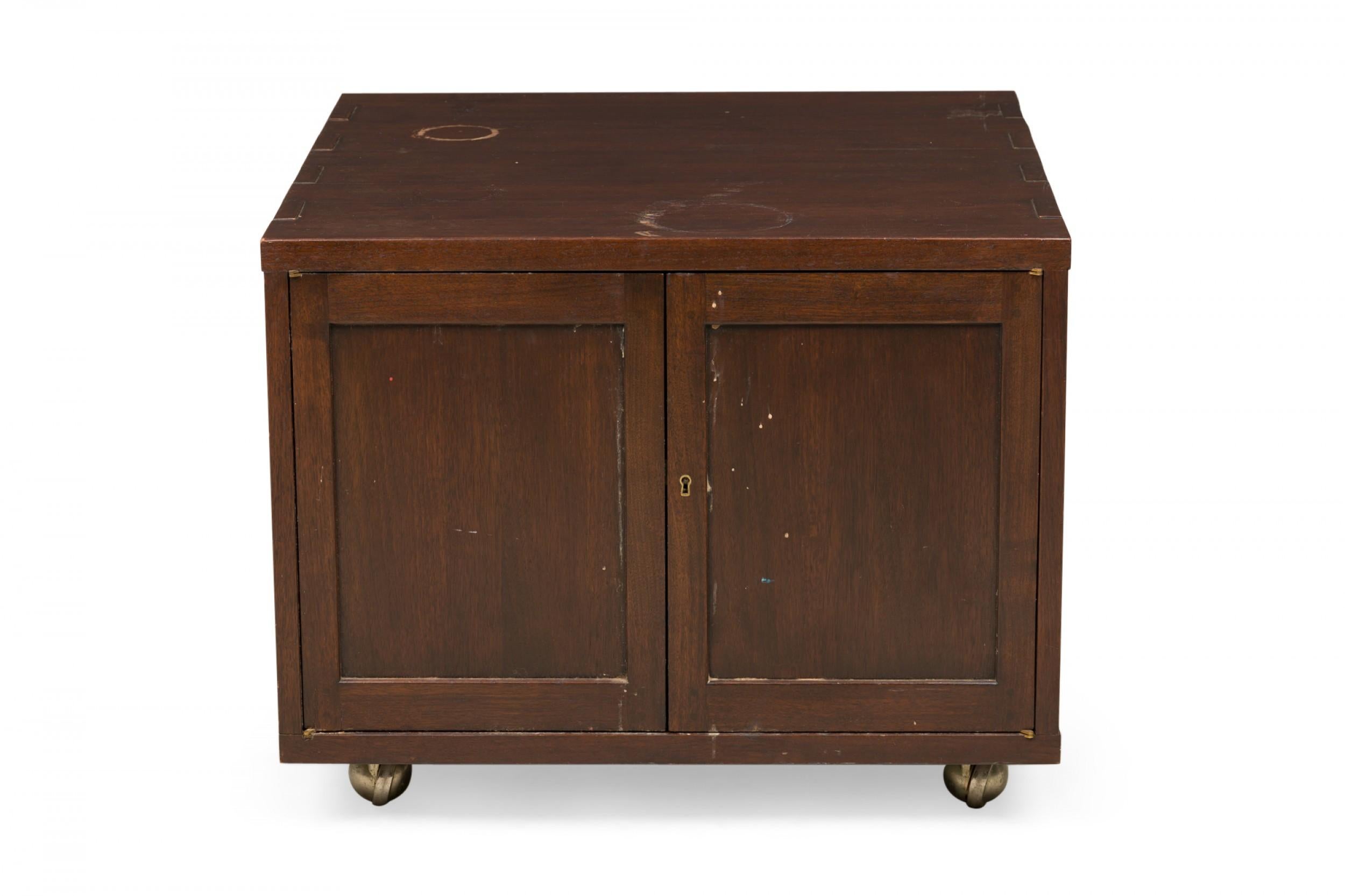 American Mid-Century cabinet with a dark stained walnut cabinet with two hinged doors, a dovetail connected top, and key hole, resting on four ball casters. (EDWARD WORMLEY FOR DUNBAR FURNITURE COMPANY)
