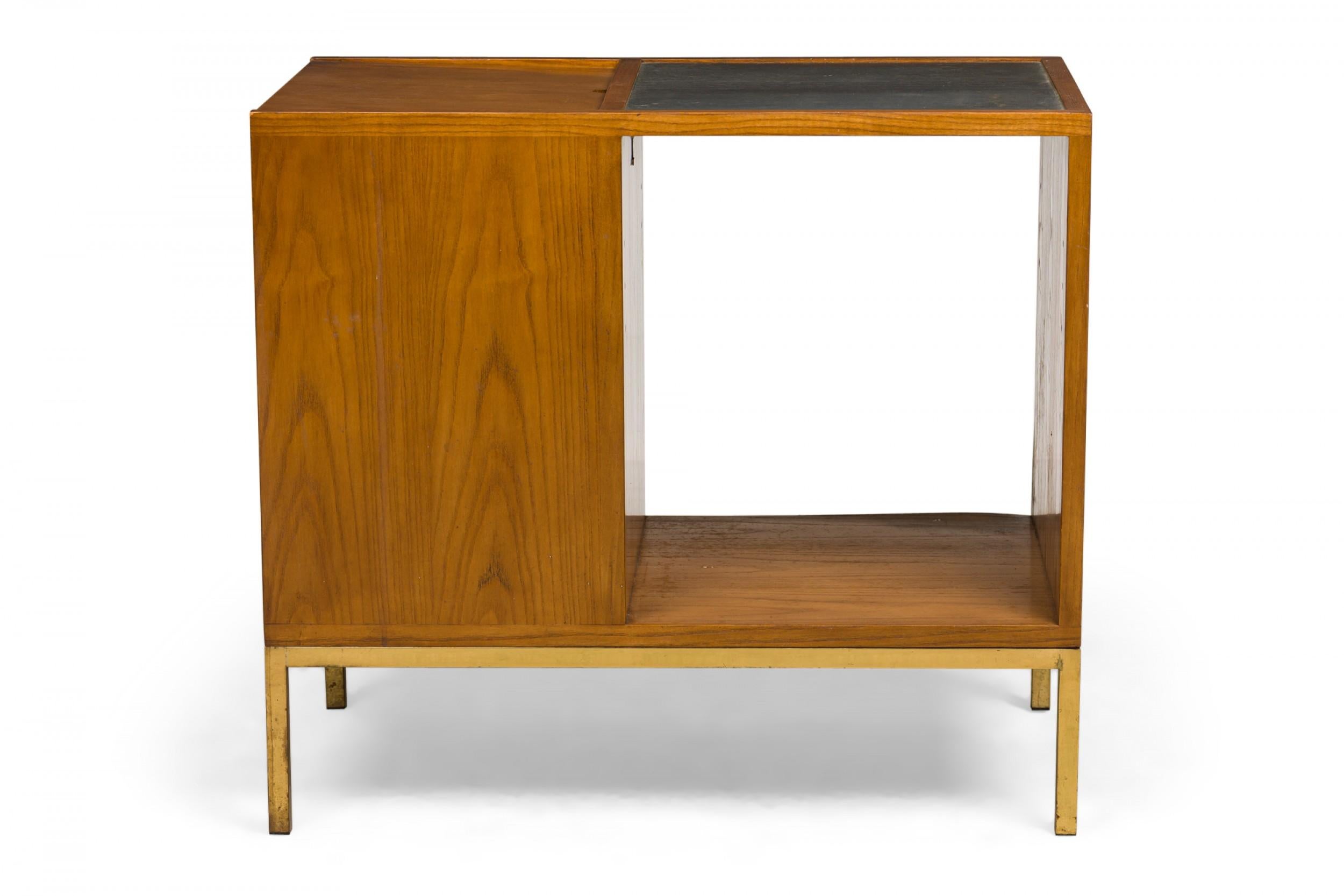 American Mid-Century dry bar cabinet with a walnut case featuring a left-hand closed cabinet next to an open shelf compartment topped with a gray slate serving area, all resting on a polished brass bracket base. (EDWARD WORMLEY FOR DUNBAR FURNITURE