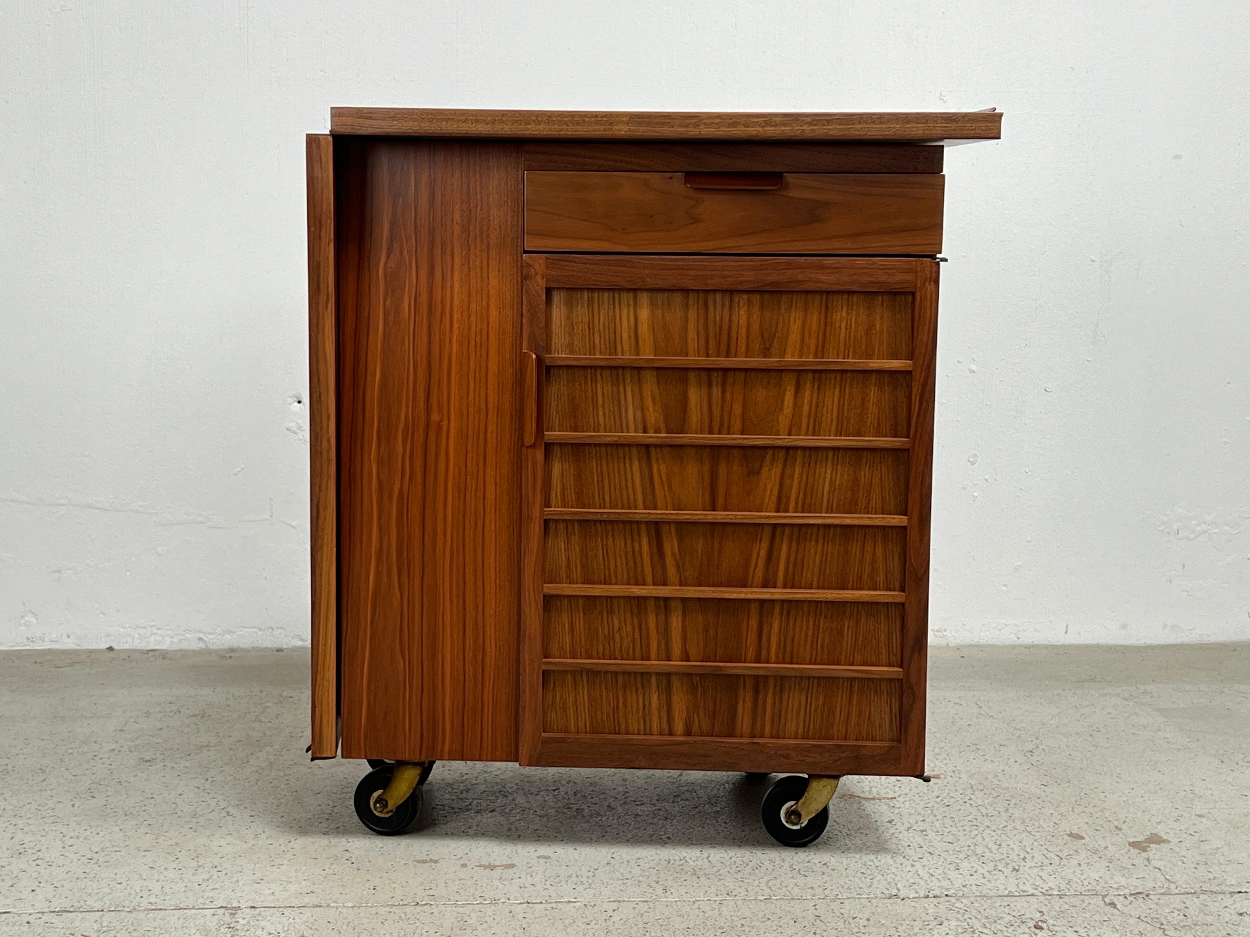 A walnut bar cart with sliding drop top. Designed by Edward Wormley for Dunbar. 
