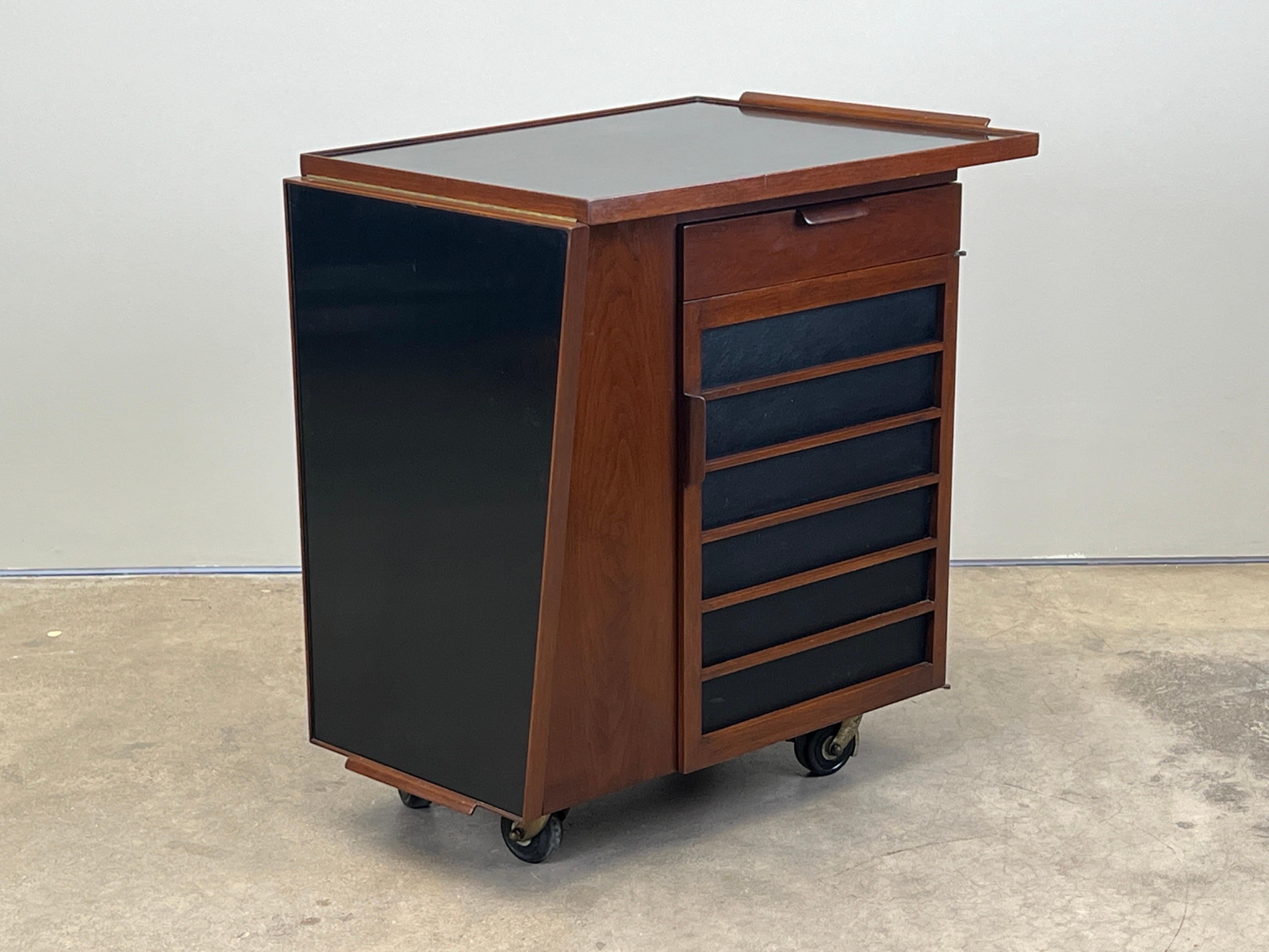 Un carrito de bar de nogal con tapa abatible deslizante laminada. Diseñado por Edward Wormley para Dunbar.
27,5 cerrado
53,25 abierto 