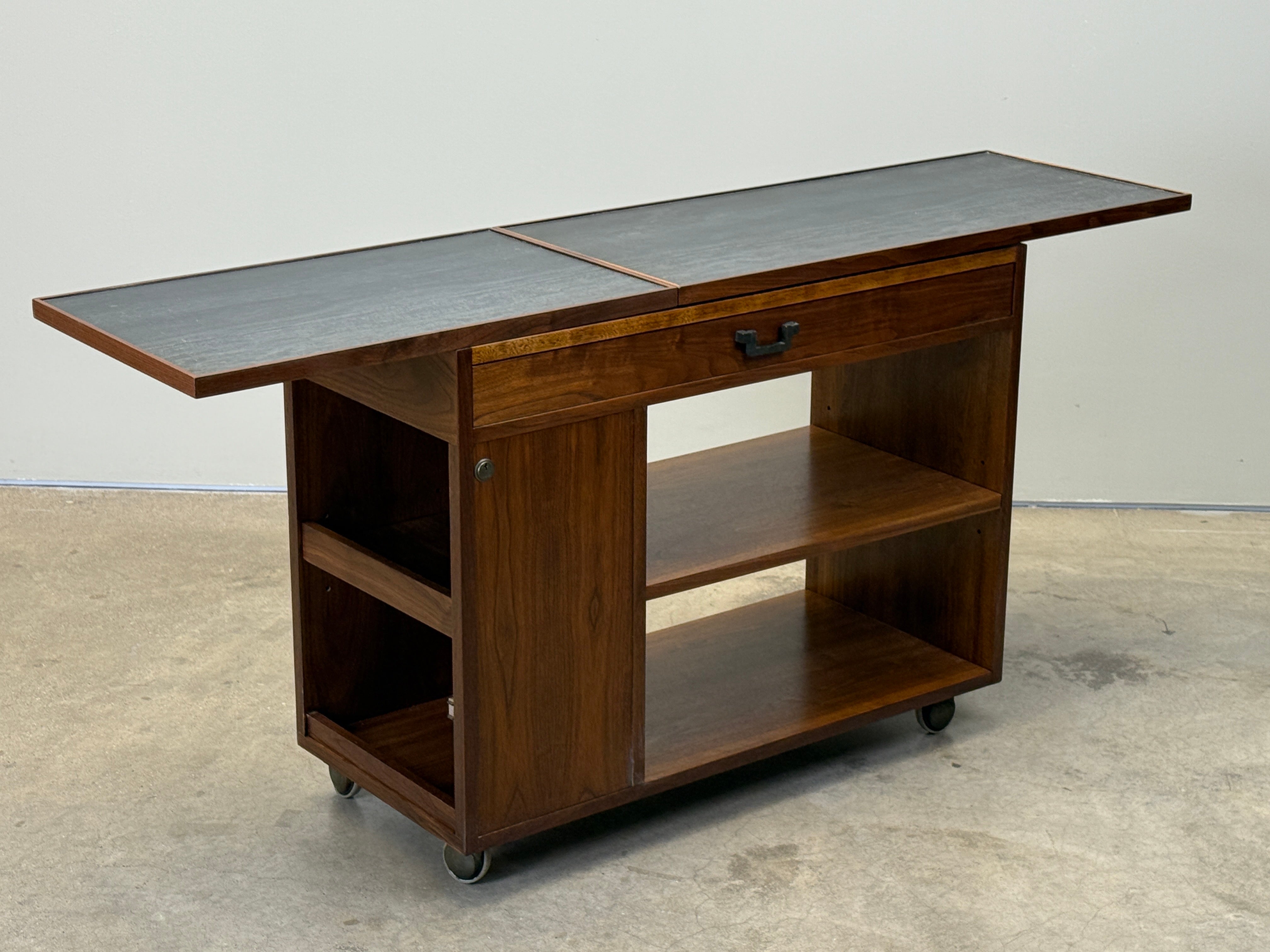 A walnut bar cart with sliding faux slate top. Designed by Edward Wormley for Dunbar.  