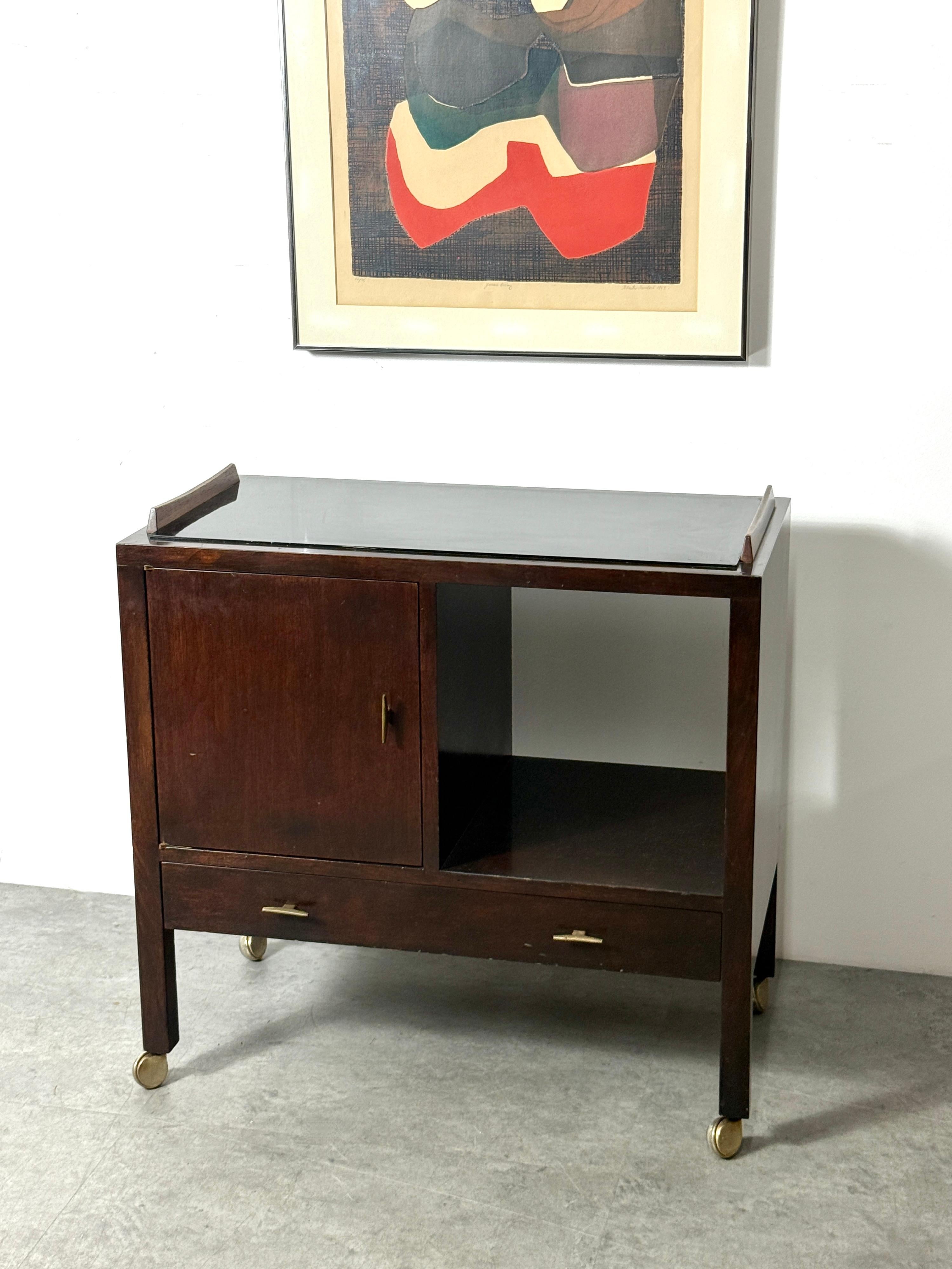 Un serveur rare conçu par Edward Wormley pour Dunbar vers les années 50

Modèle 460 en noyer teinté foncé avec une surface fixe laquée noire encadrée par des baguettes en bois de rose sculpté.

Armoire simple à côté d'un compartiment d'exposition