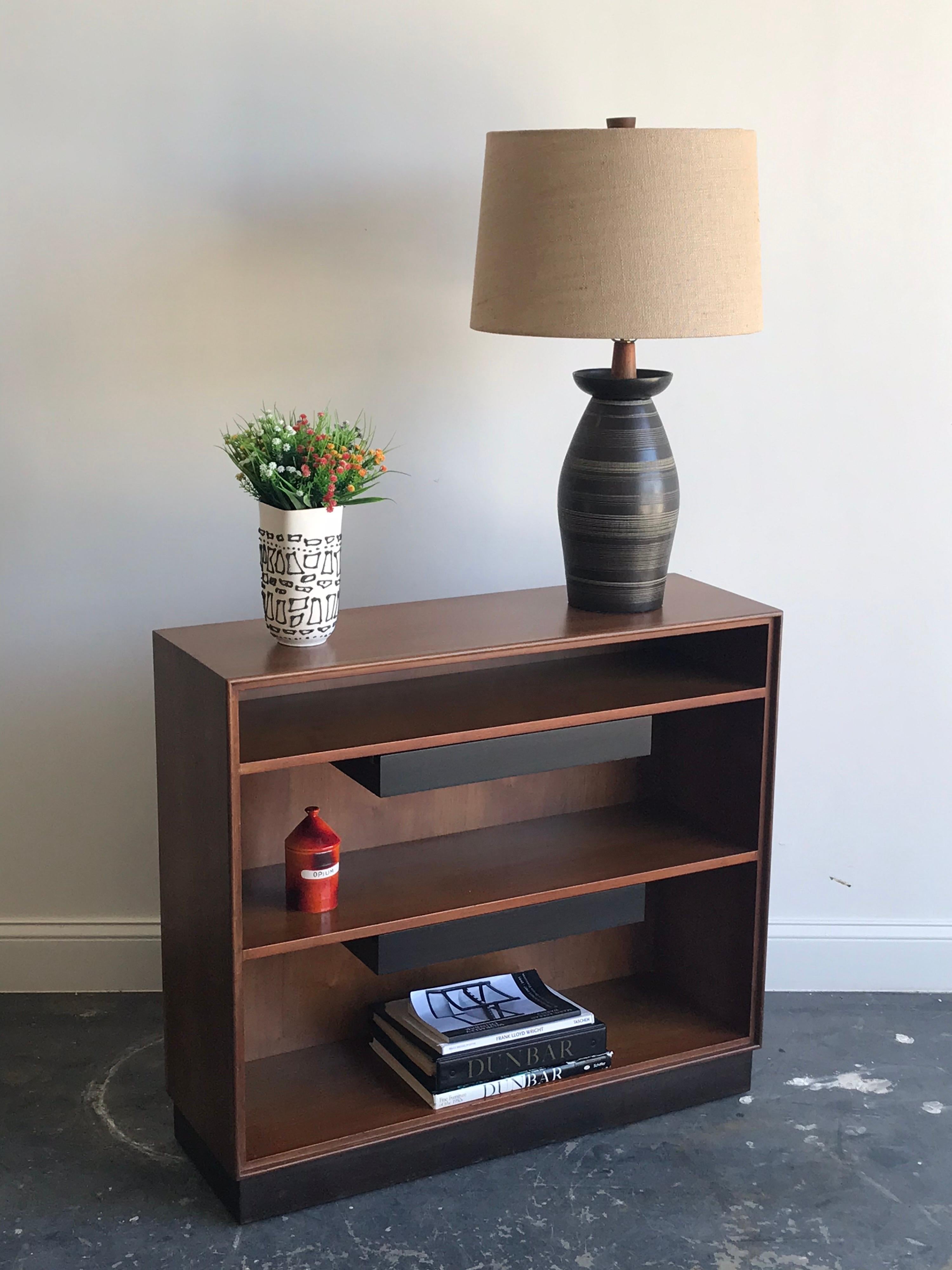 An Edward Wormley designed bookcase for Dunbar. Both shelves have a floating drawer that hangs from below. Walnut case has been refinished, and interior shelves have been cleaned. Interior has a wonderful glowing patina. Base is wrapped in the