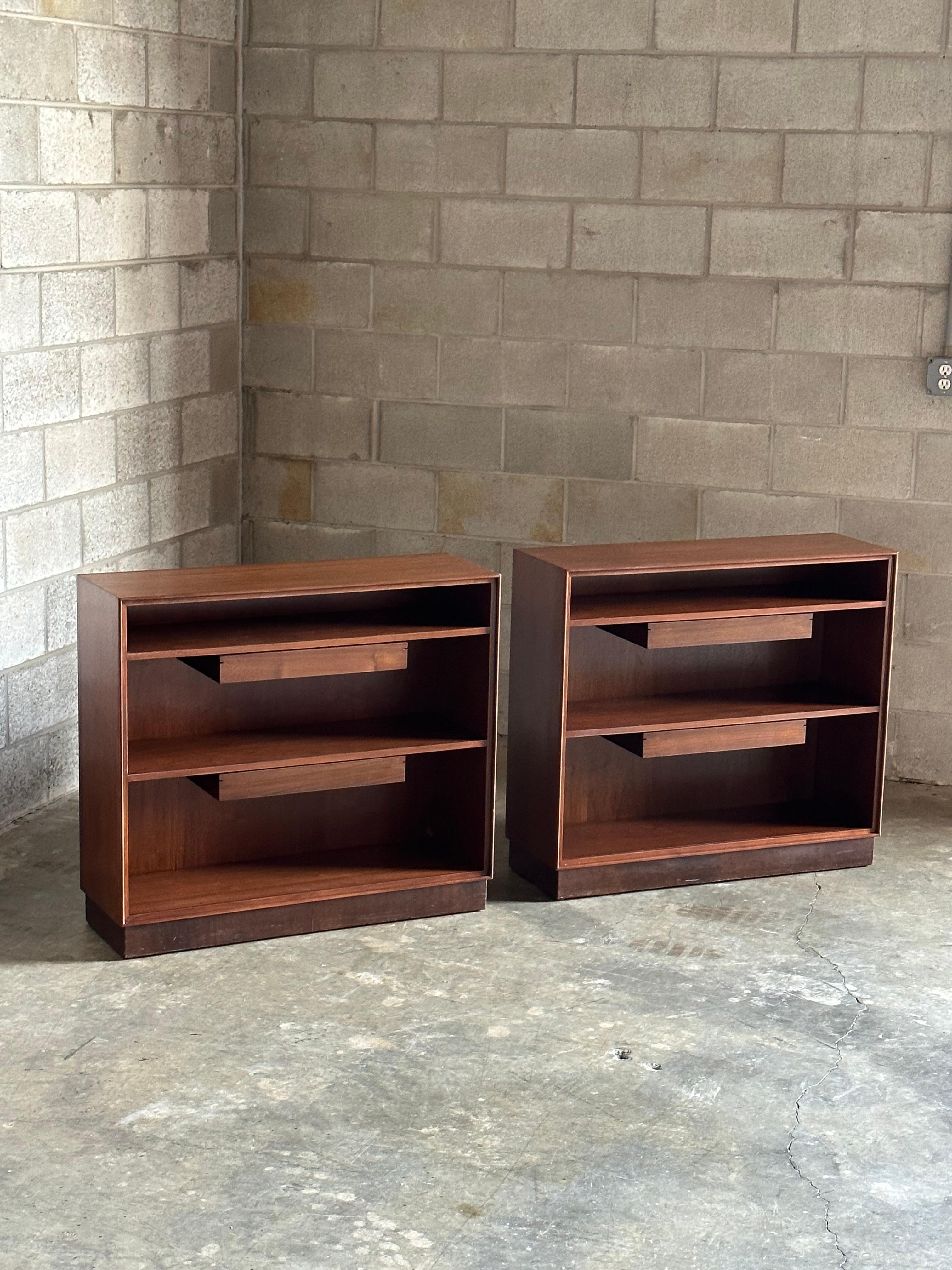 An Edward Wormley designed bookcase for Dunbar. Both shelves have a floating drawer that hangs from below. Beautiful walnut case with a base wrapped in the original leather which shows beautifully.

Could be pushed together to use as a long bookcase