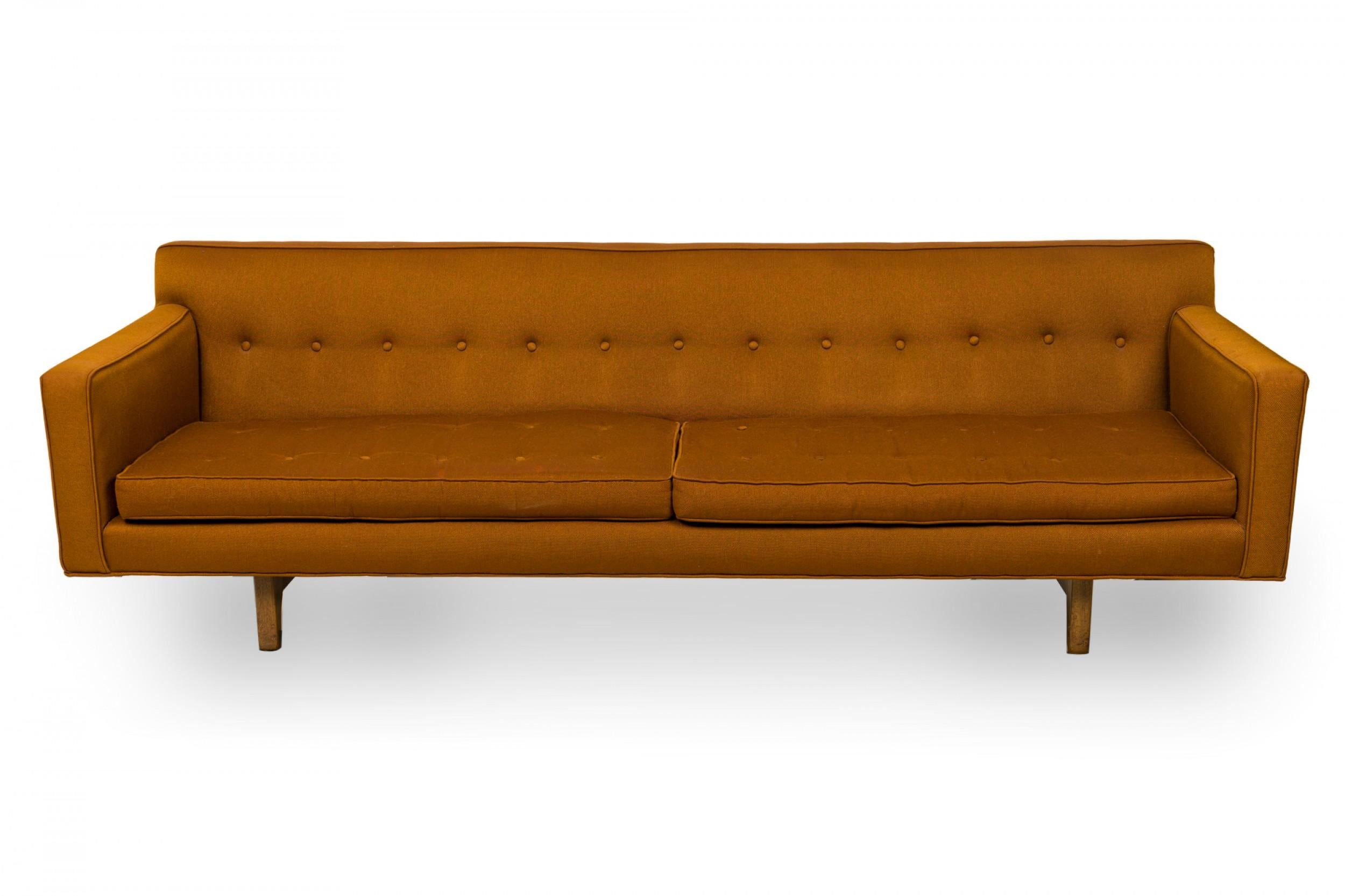 American mid-century 3-seat sofa with brown button tufted fabric upholstery, and two removable seat cushions resting on a floating wooden base. (EDWARD WORMLEY FOR DUNBAR FURNITURE COMPANY)
 