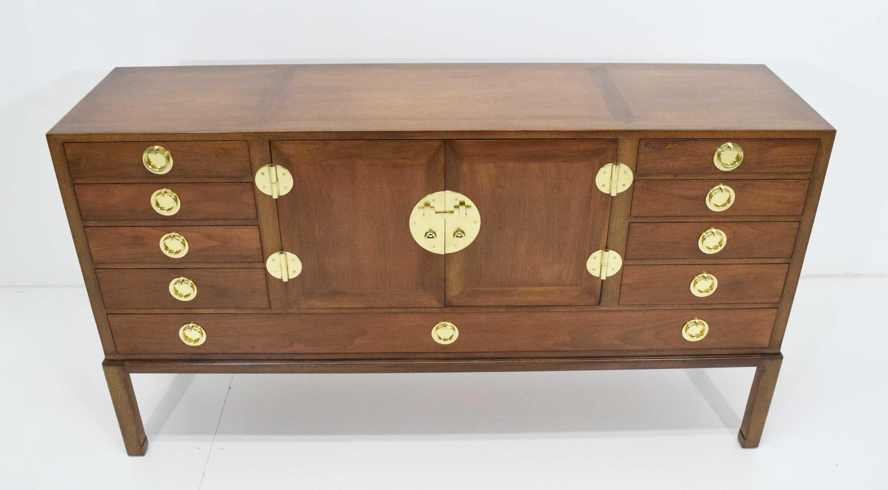 Beautiful sideboard cabinet designed by Edward Wormley for Dunbar, made of sandalwood with solid brass hardware. Cabinet has drawers on each side, center Lucite pull out shelf and one glass interior shelf. Three drawers with interior utility trays.