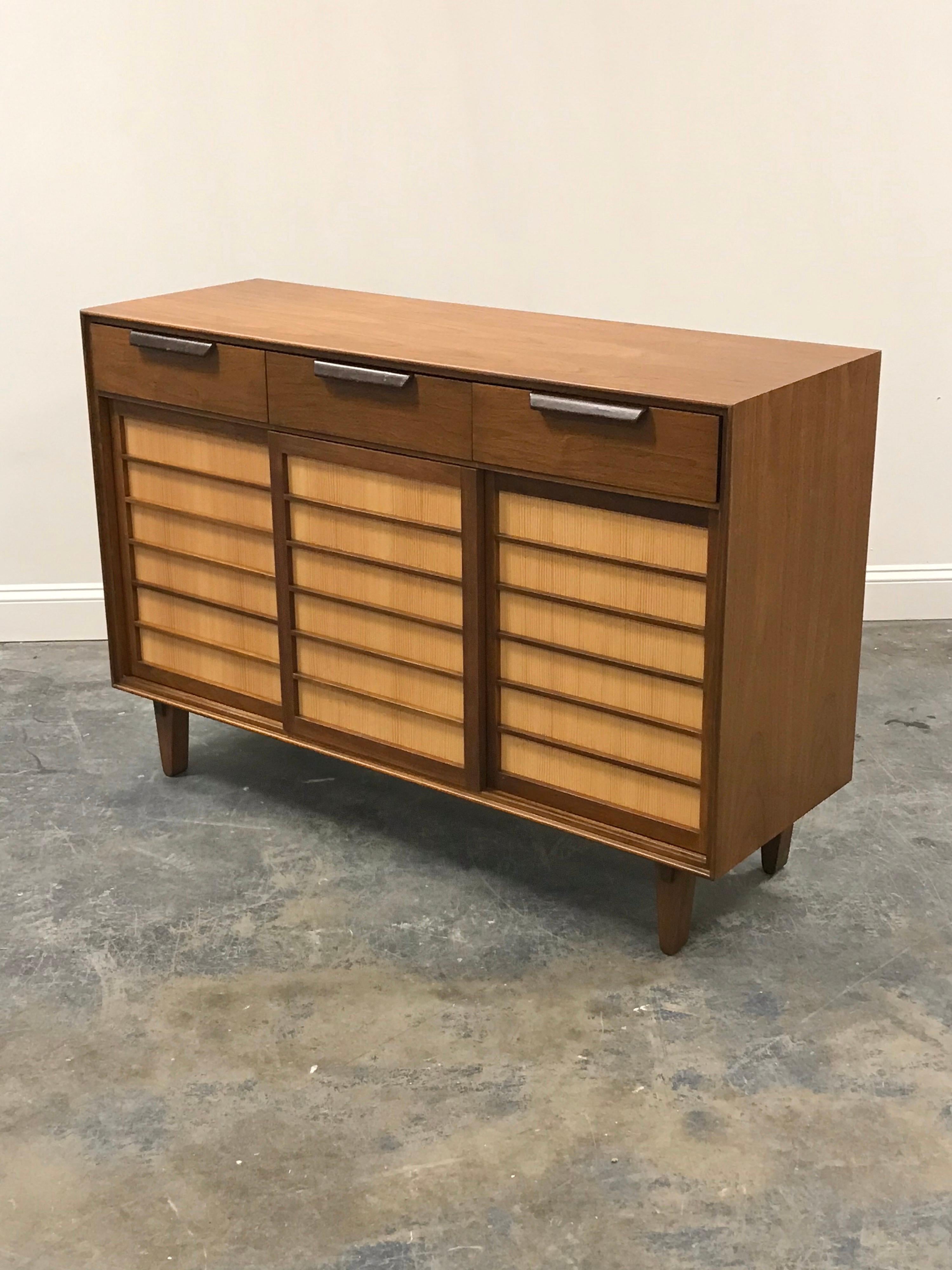 Early sideboard/ credenza/ buffet designed by Edward Wormley for Dunbar. Walnut case, pine-backed sliding doors with walnut slats, and leather handles. Right side features two sliding trays, left/middle have two adjustable height shelves. Exterior