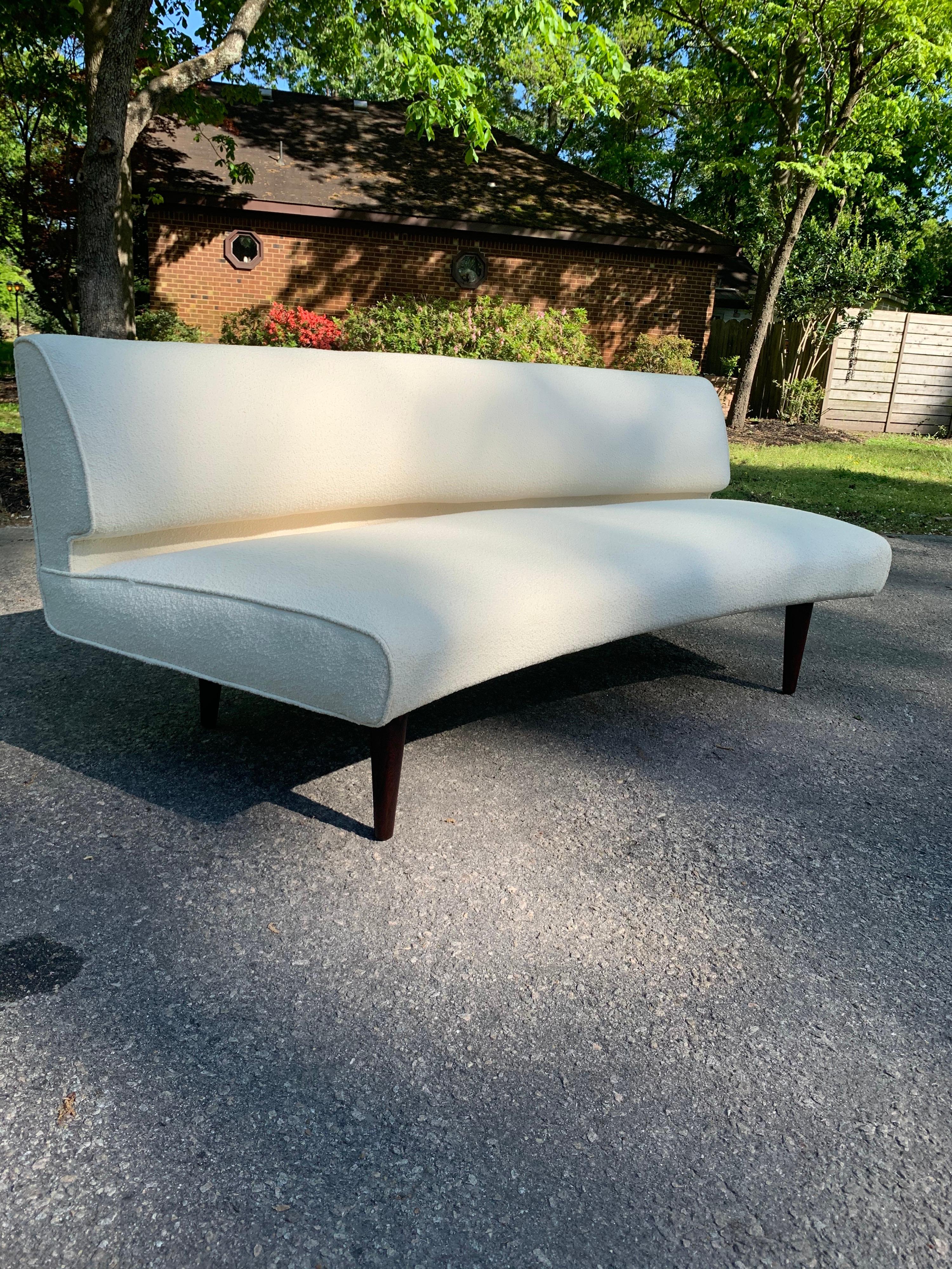 A vintage Edward Wormley for Dunbar model 4851a curved sofa. This sofa has a channel back and has been upholstered in Knoll Classic Boucle ivory fabric. This sofa sits on 10