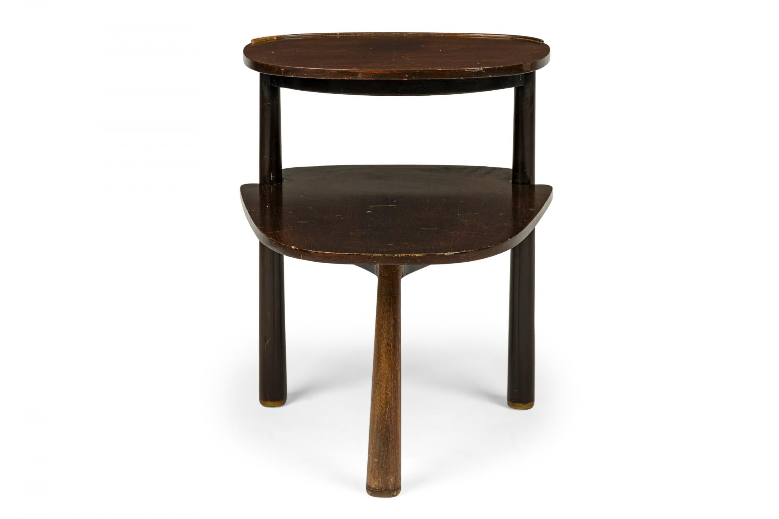 American Mid-Century stepped end / side table with an oblong profile and smaller demilune upper shelf connected to the table top by two dowel supports, resting on three reverse tapered dowel legs. (EDWARD WORMLEY FOR DUNBAR FURNITURE COMPANY).