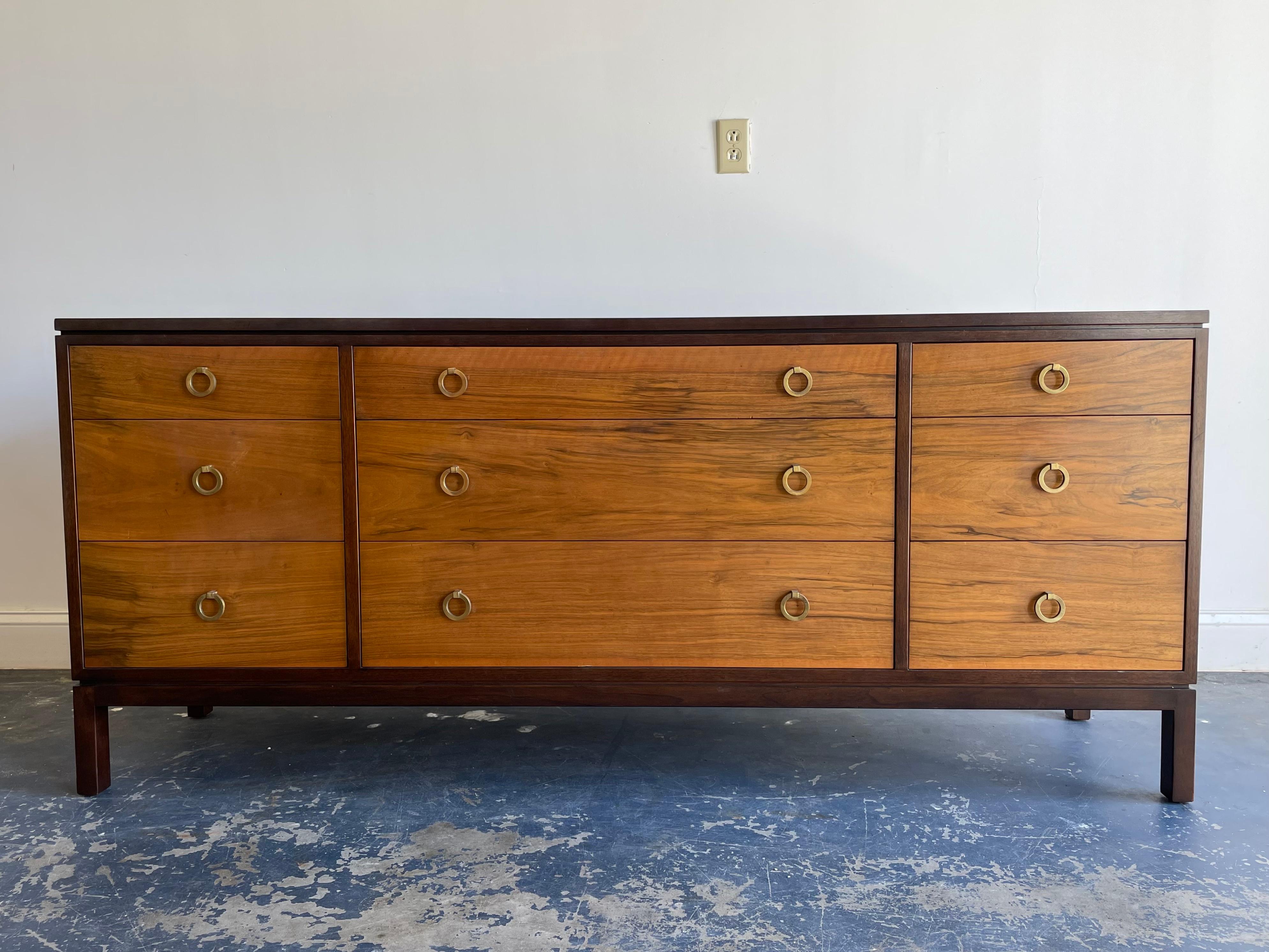 Elegant long dresser by Edward Wormley for Dunbar. Features graduating drawers with 6 smaller drawers and three long drawers in the middle. Brass ring pulls highlight piece. 

Please message for video to accurately depict condition of top as