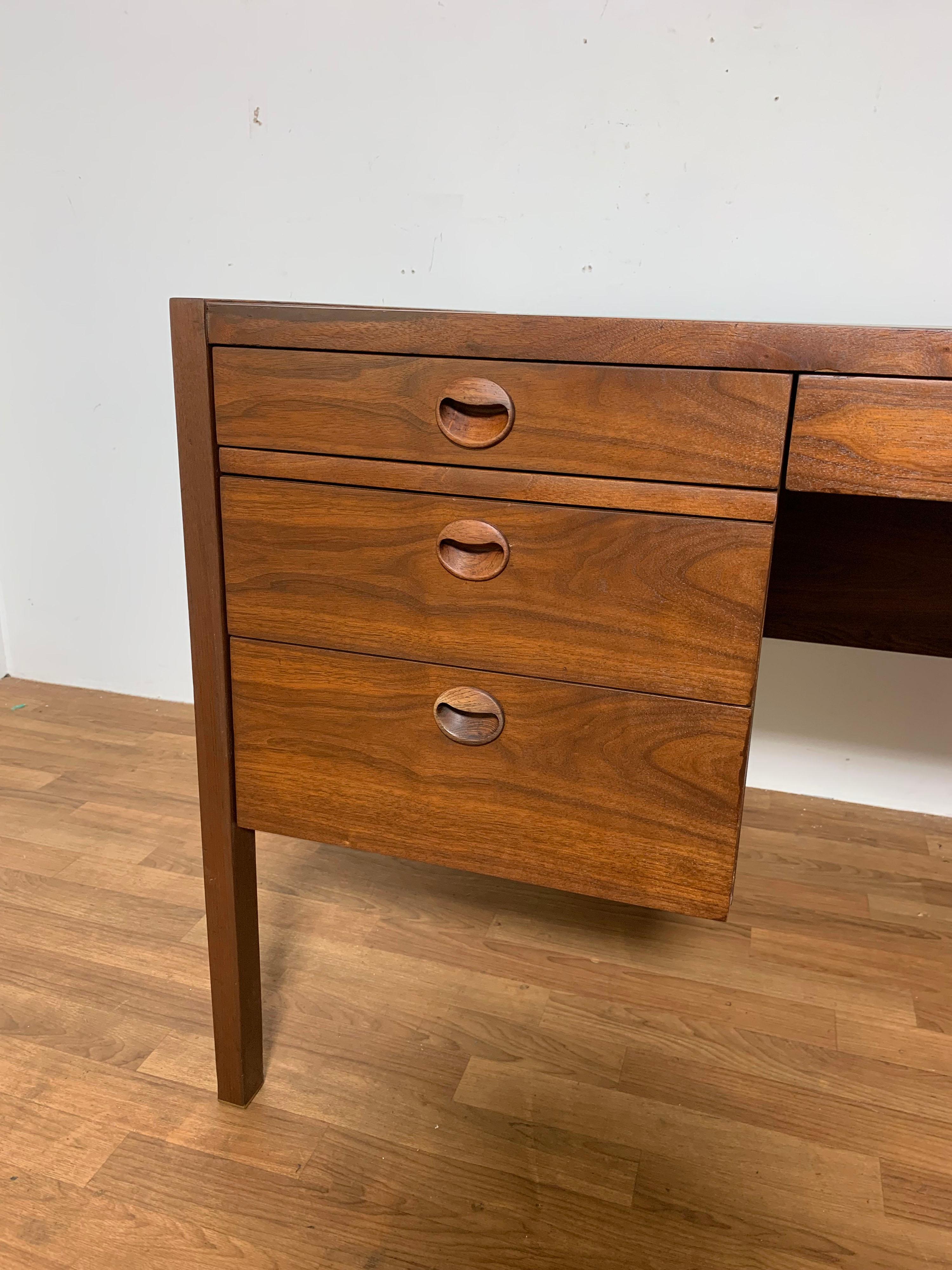 Executive desk with six drawers in walnut with rosewood drawer pulls by Edward Wormley for Dunbar, ca. 1950s. Features a kick screen, a file drawer, two sliding returns, and brass feet.