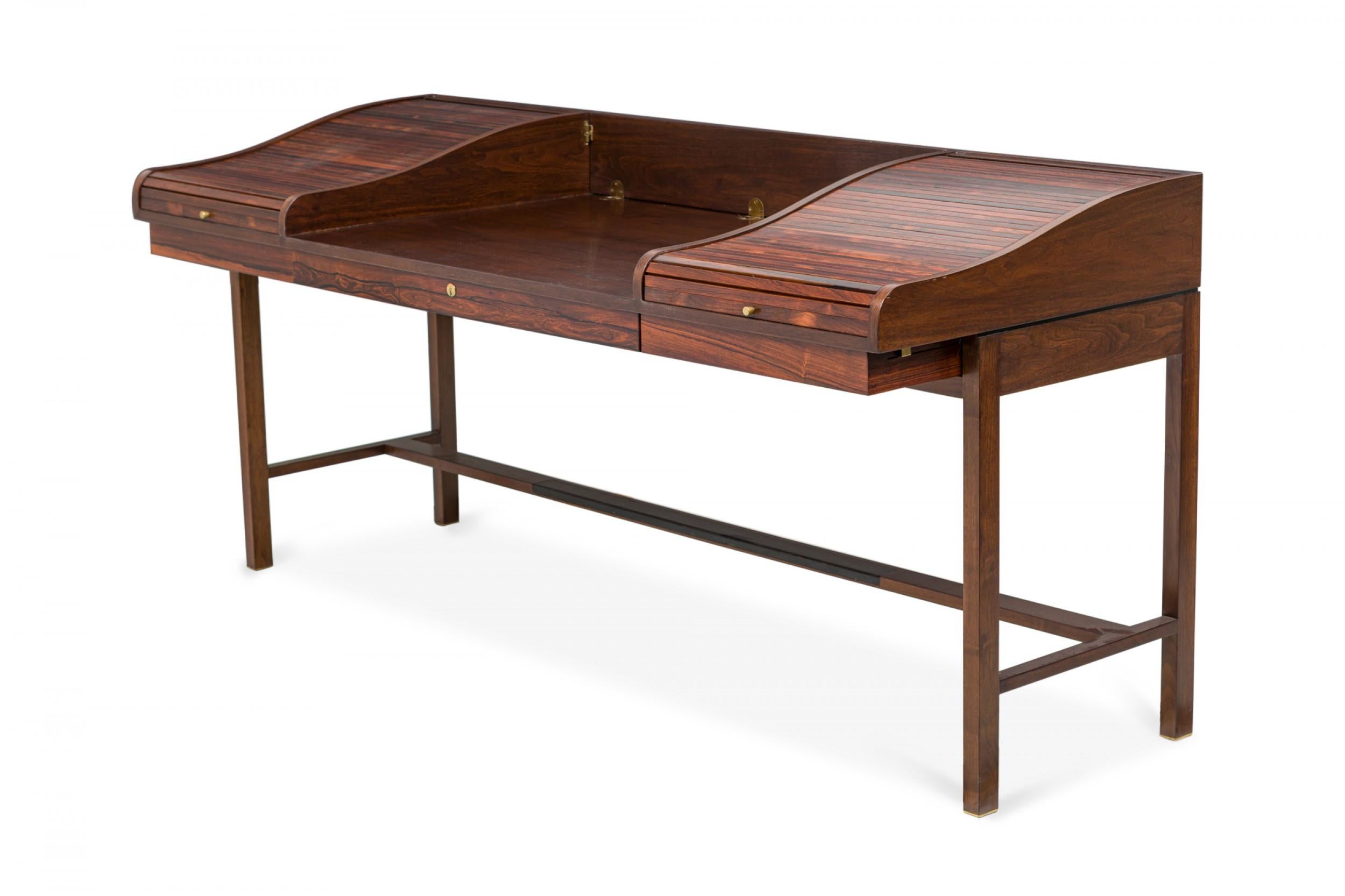 American Mid-Century rosewood and mahogany desk with two tambour roll top outer sections with brass hardware that open to reveal workspace and compartments, with an open central workspace and a back rail that folds to create a partners desk, resting