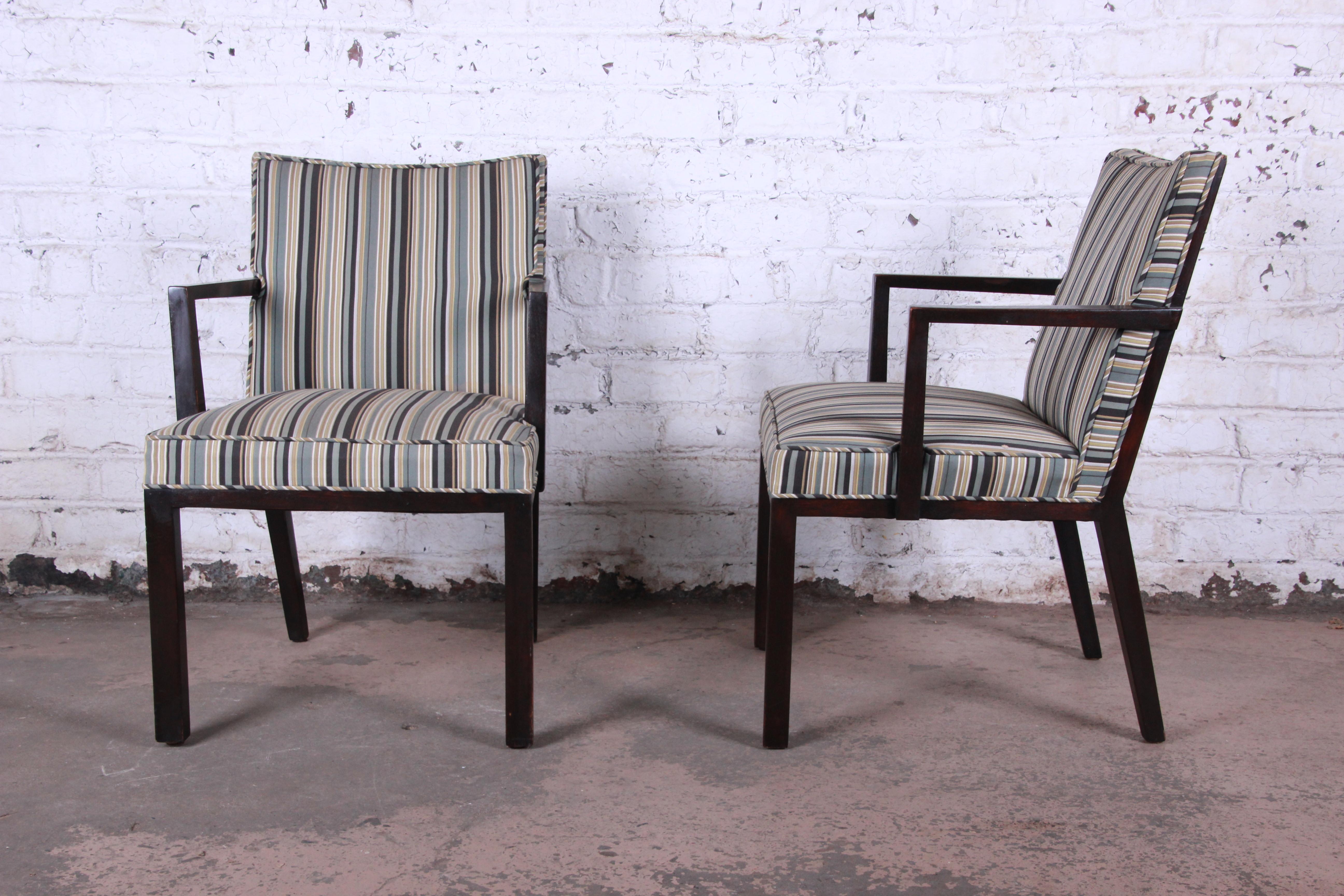 An exceptional pair of armchairs designed by Edward Wormley for Dunbar Furniture. The chairs feature sleek mid-century modern design and solid dark mahogany frames. The striped upholstery is in good condition and ready for use. The original Dunbar