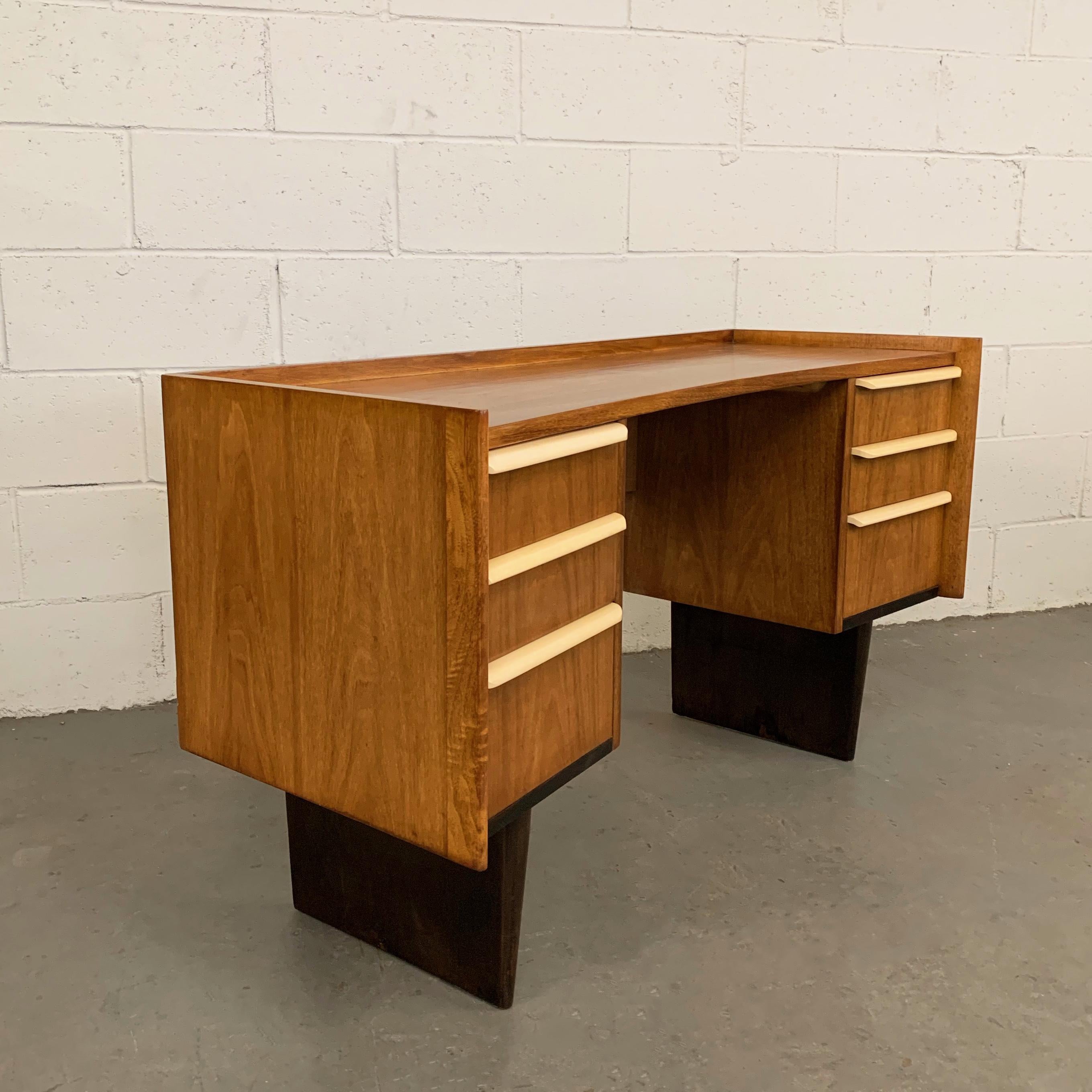 Mid-Century Modern, double pedestal, tri-tone, vanity writing desk by Edward Wormley for Dunbar features a medium mahogany body sitting on slender, ebonized bases with lacquered beige drawer handles. The height of the desk surface is 25.25 inches